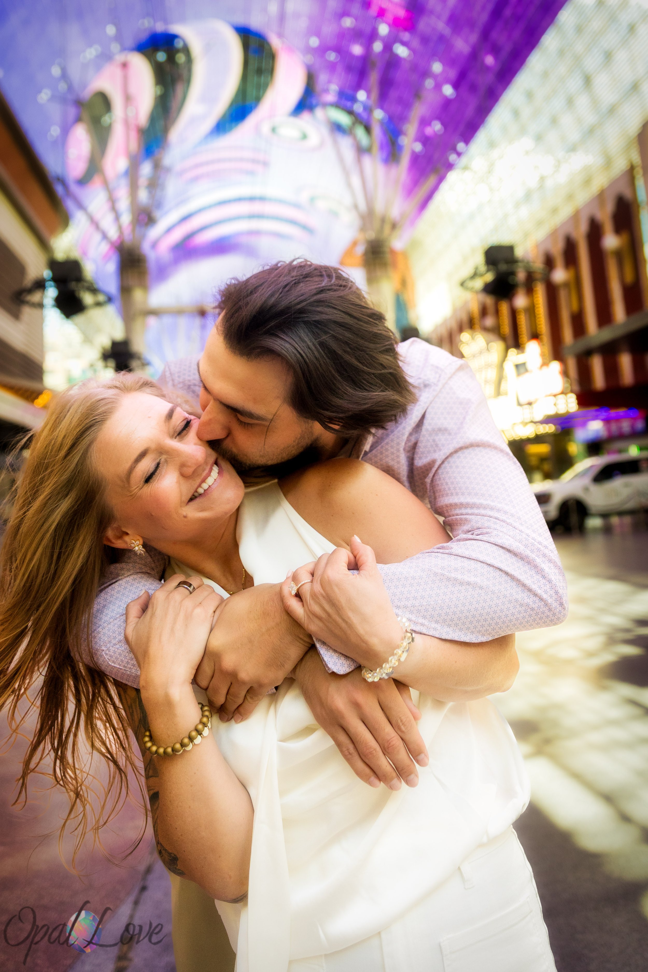 Newly engaged couple laughing together under the glowing Fremont Street canopy lights during their Las Vegas engagement photos.