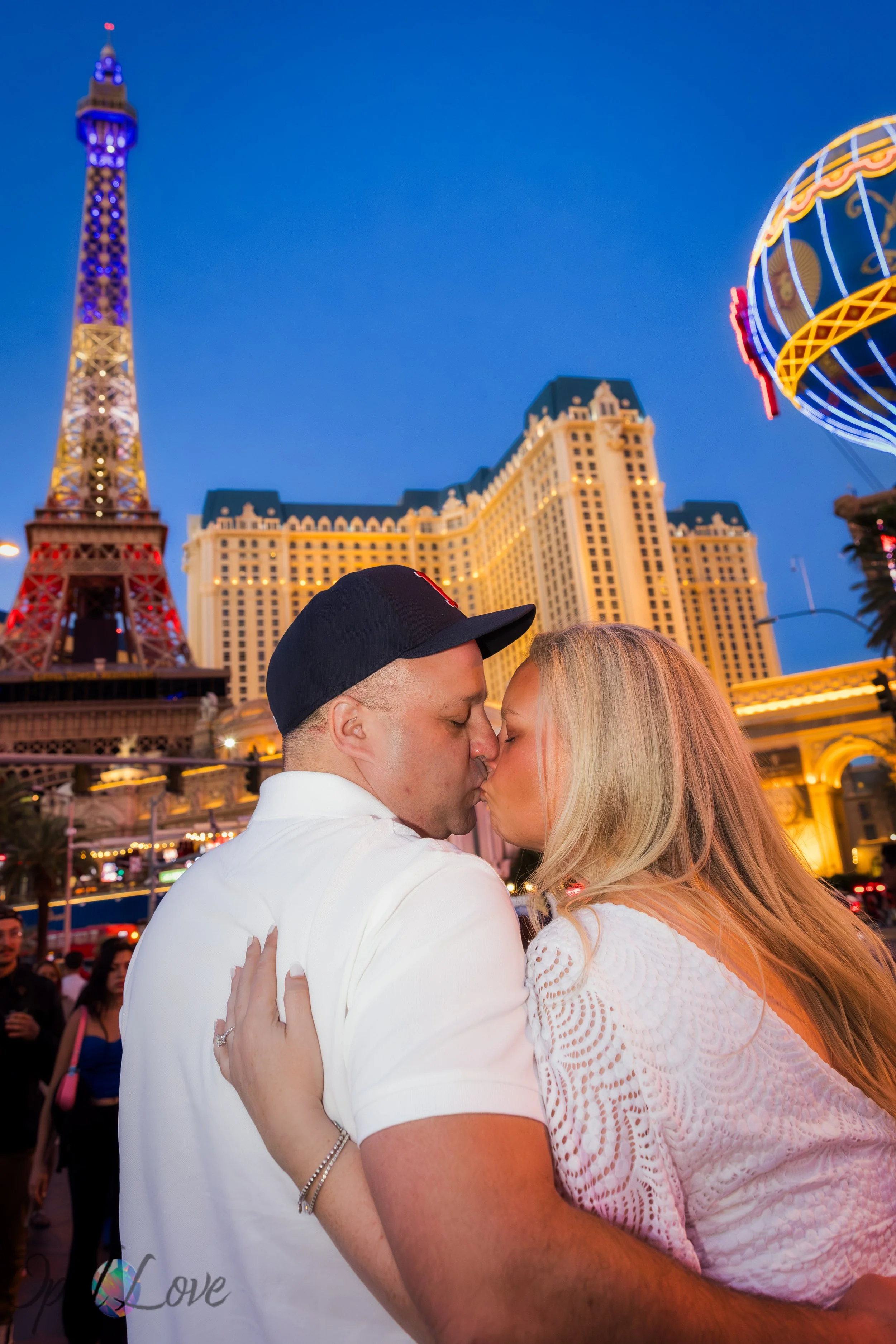 Couple kissing with colorful Las Vegas Strip lights and Paris balloon in the background.