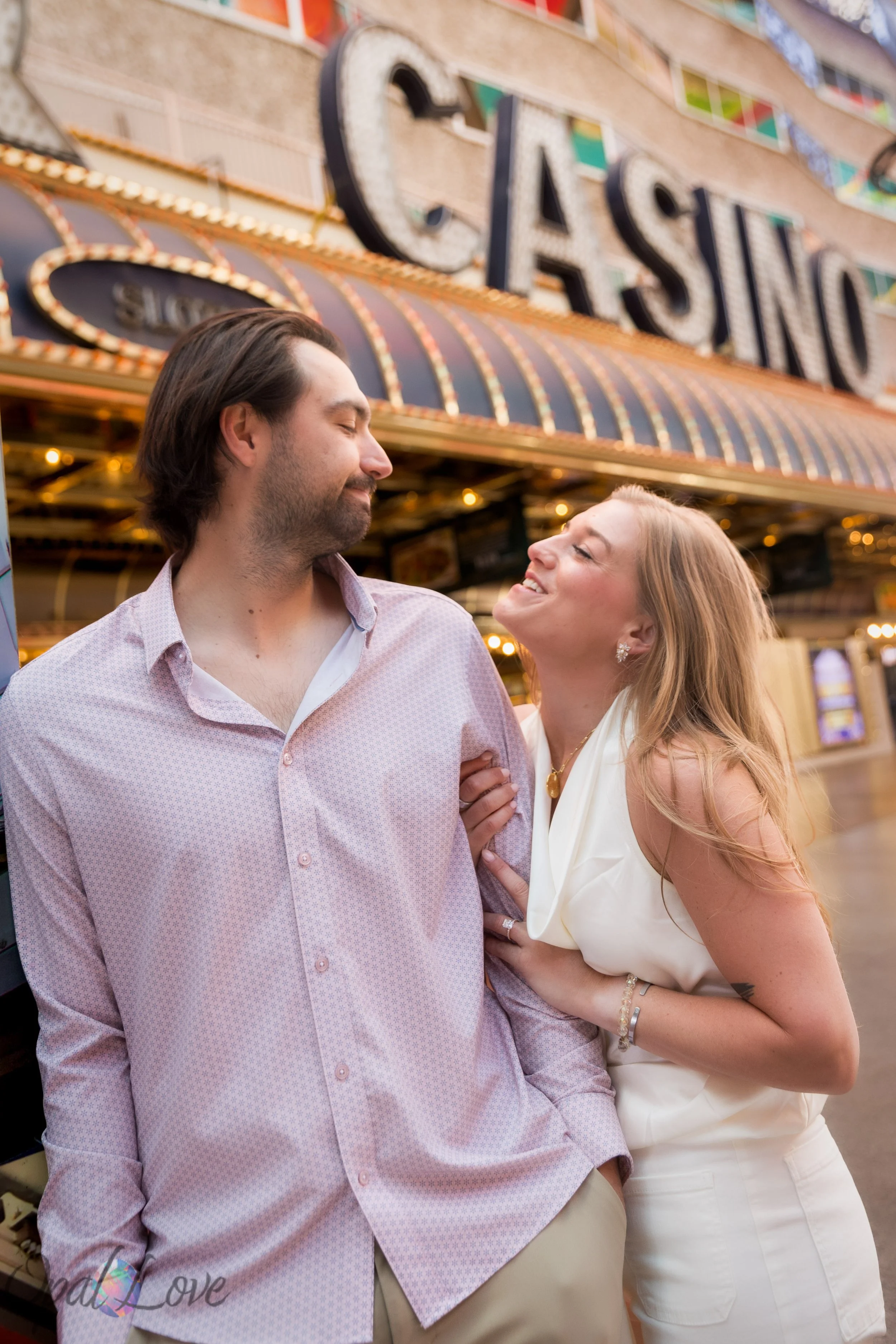 Engaged couple standing together in front of the classic Casino marquee sign on Fremont Street.