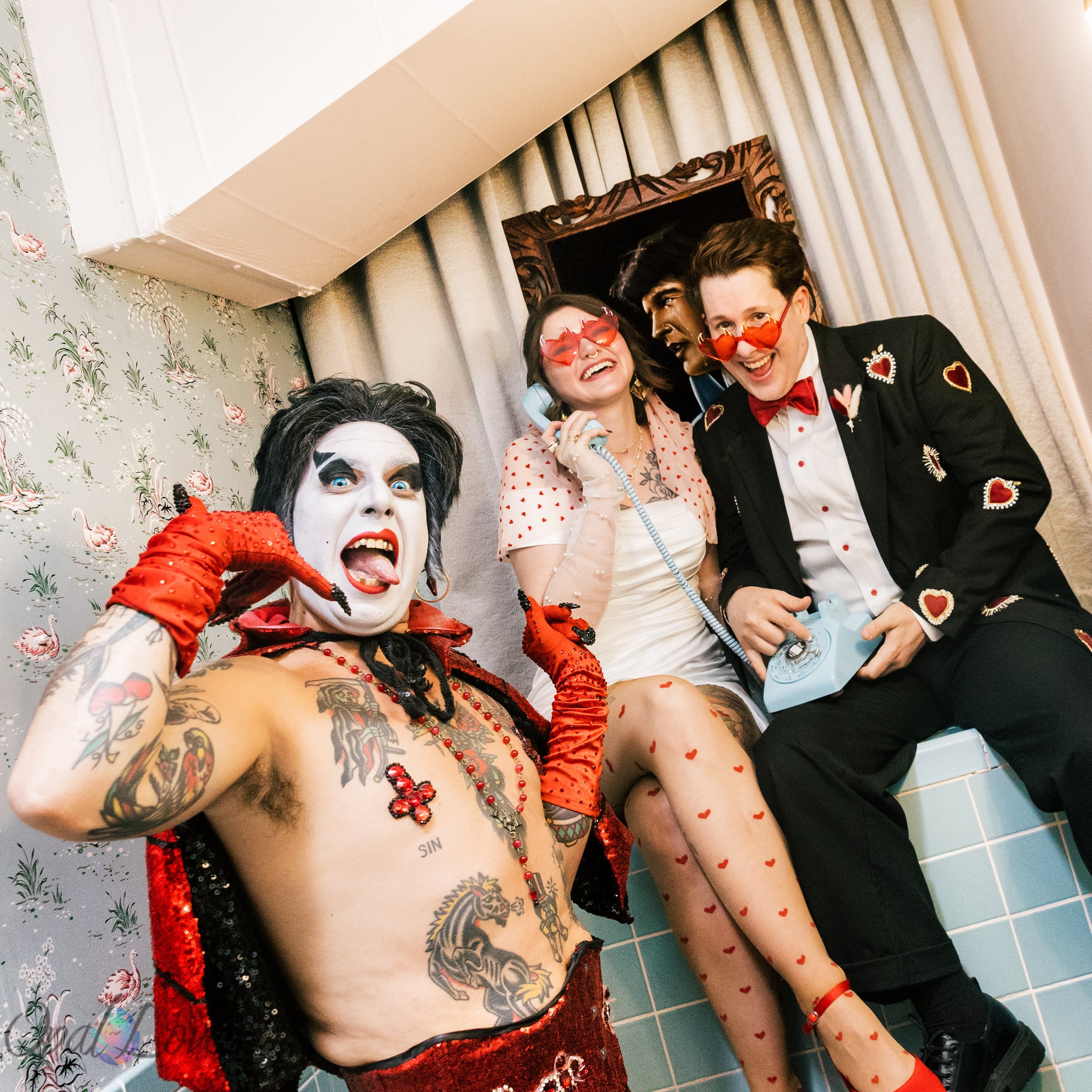 Wedding couple in clown makeup posing with a costumed performer for a playful chapel portrait.