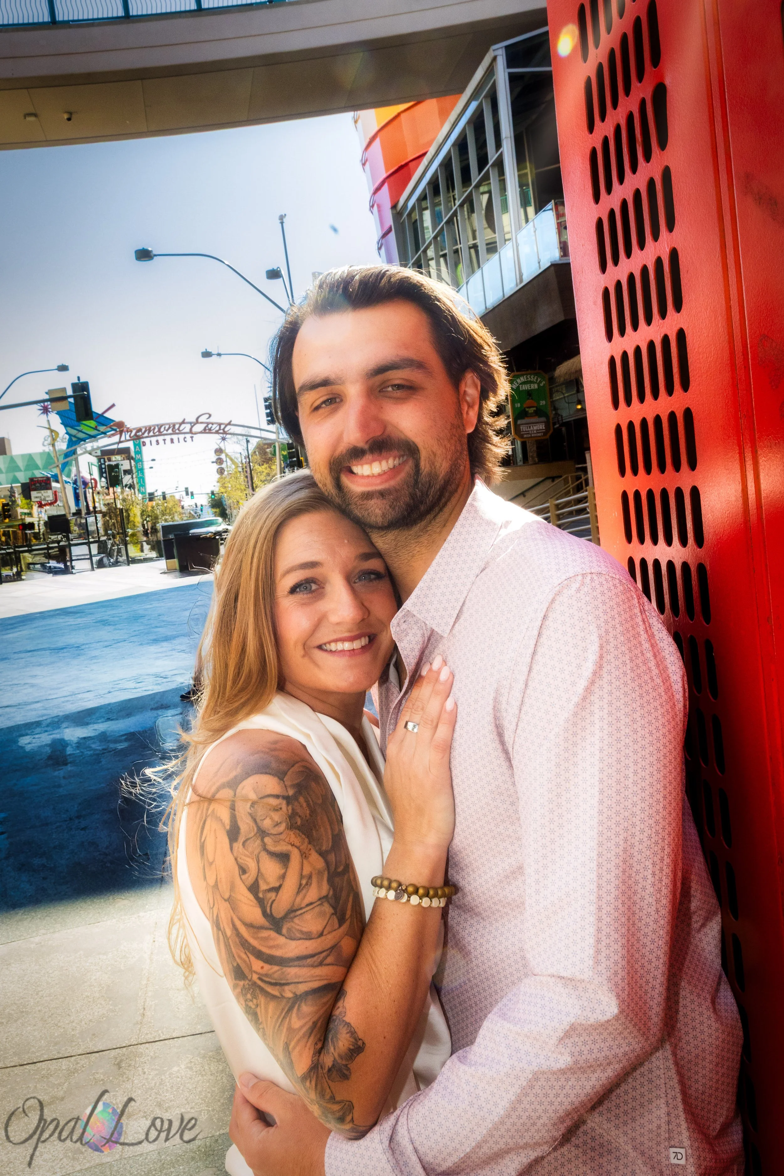 Newly engaged couple hugging beside a red architectural wall in the Fremont East entertainment district.