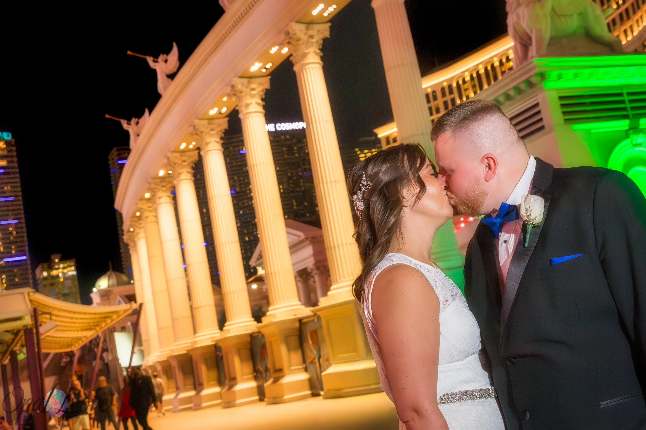 Couple kissing in front of the tall illuminated columns at Caesars Palace.