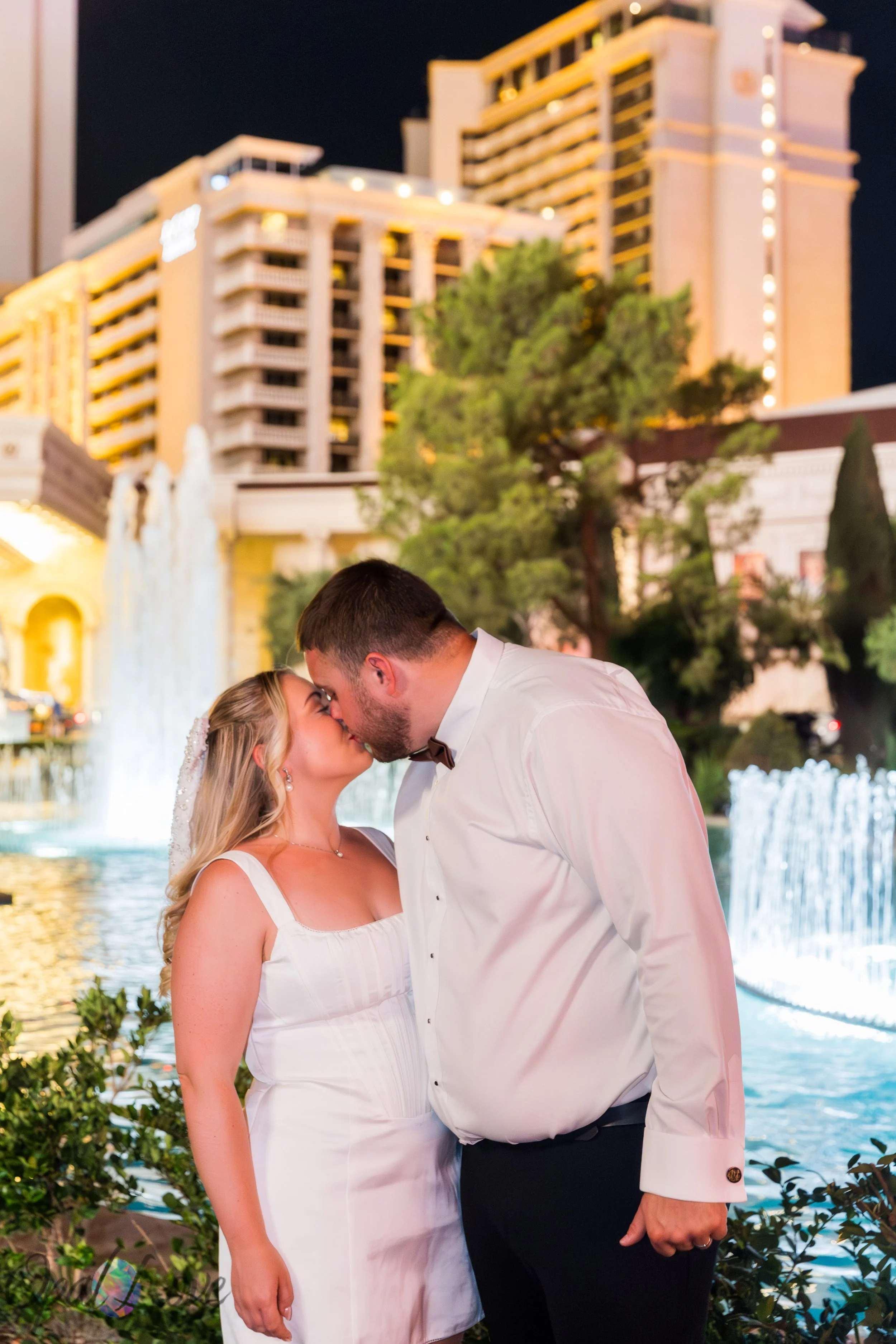 Couple kissing beside the fountains at Caesars Palace during a Las Vegas honeymoon photography session.