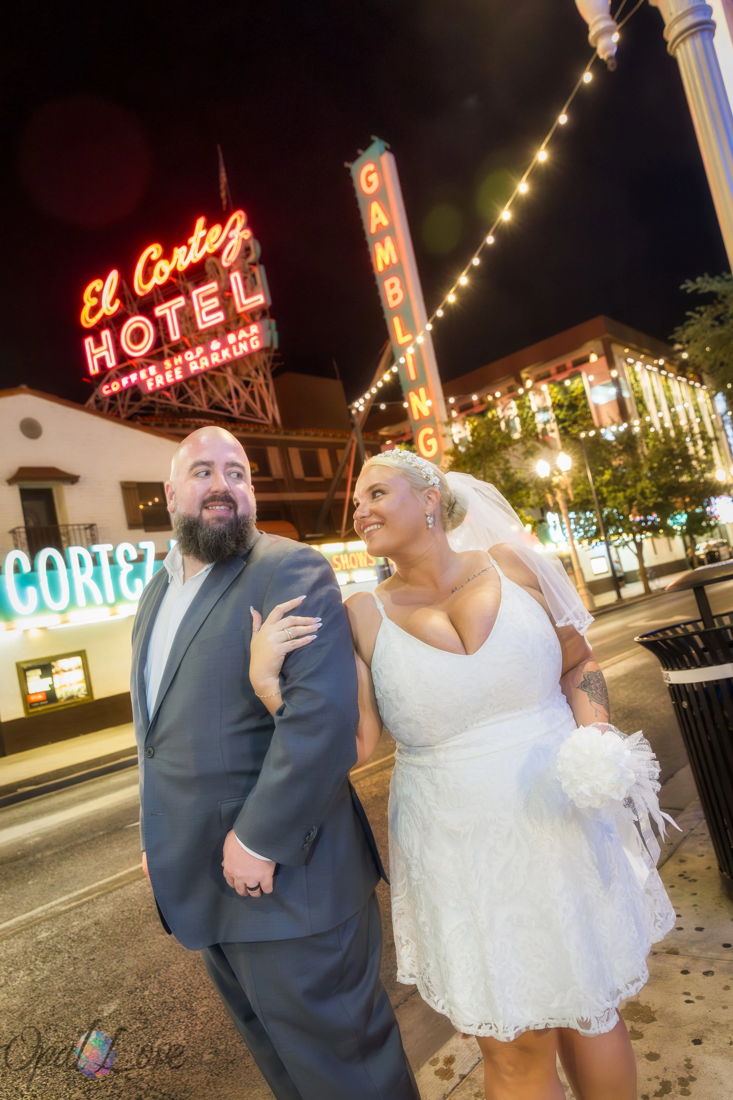 Bride and groom walking under the El Cortez sign during their Fremont Street wedding photos.