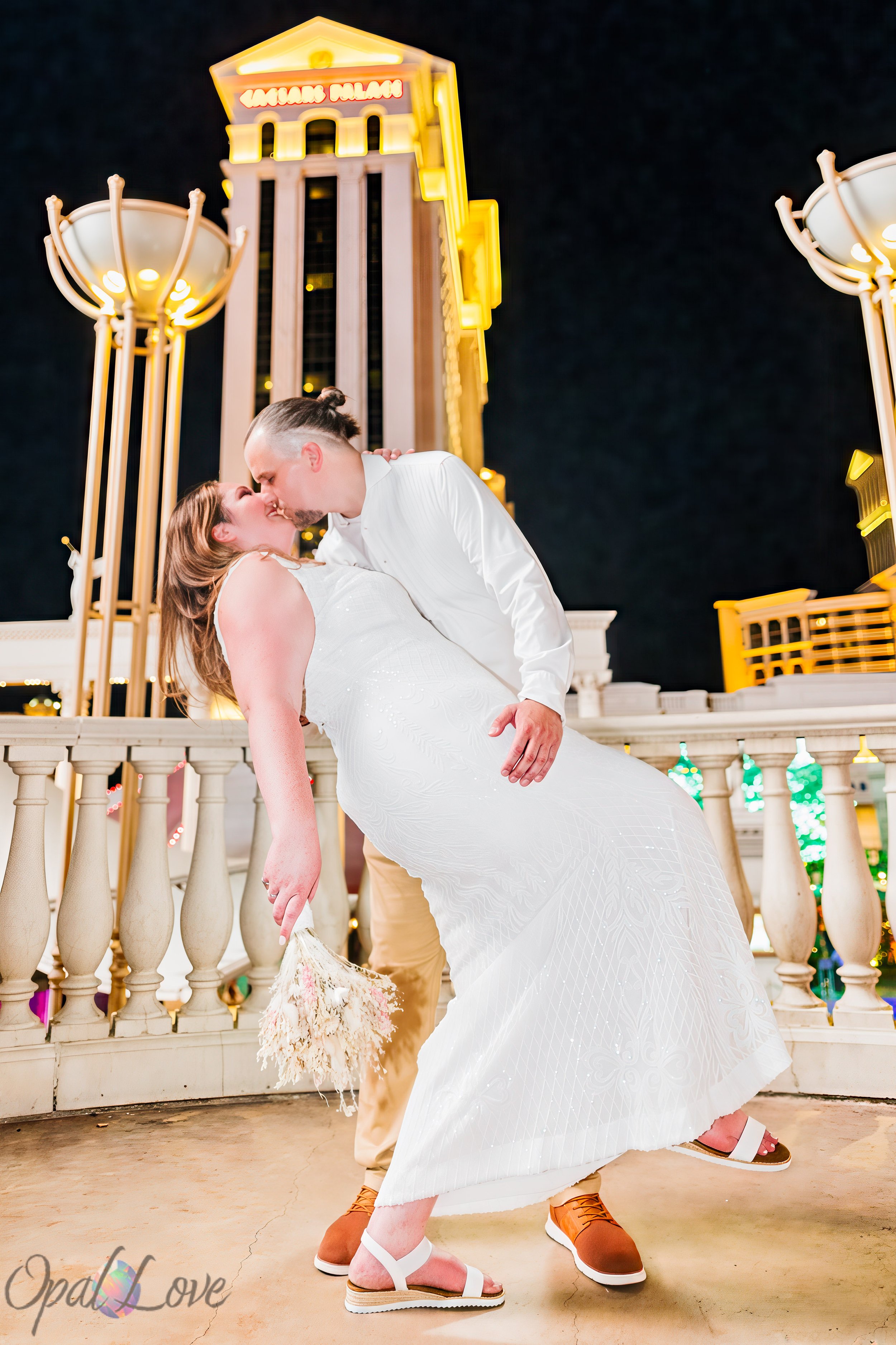 Dustin dipping Jacqueline for a kiss with Caesars Palace illuminated behind them during their Las Vegas vow renewal photography session.