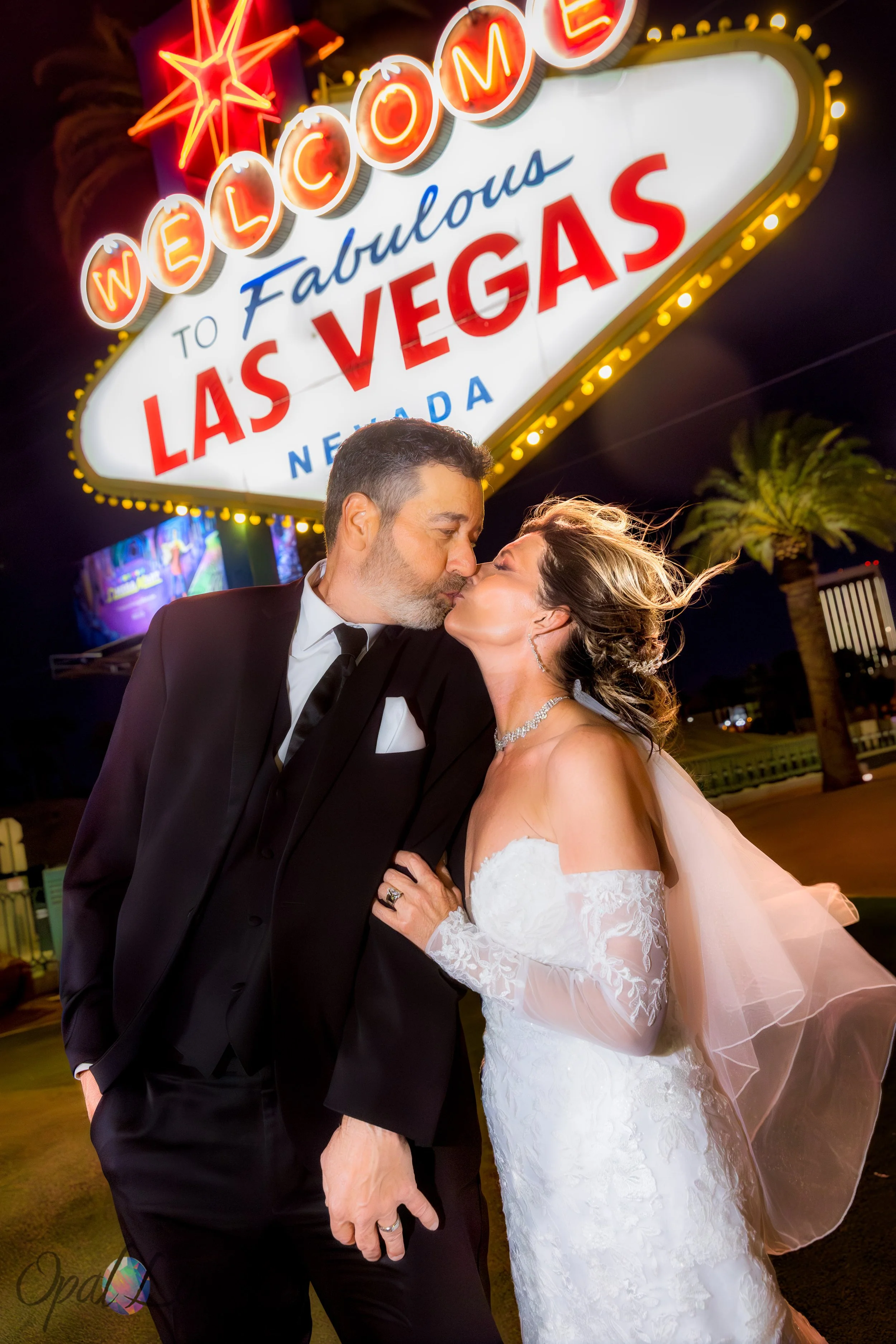 Couple kissing beneath the Welcome to Fabulous Las Vegas sign.