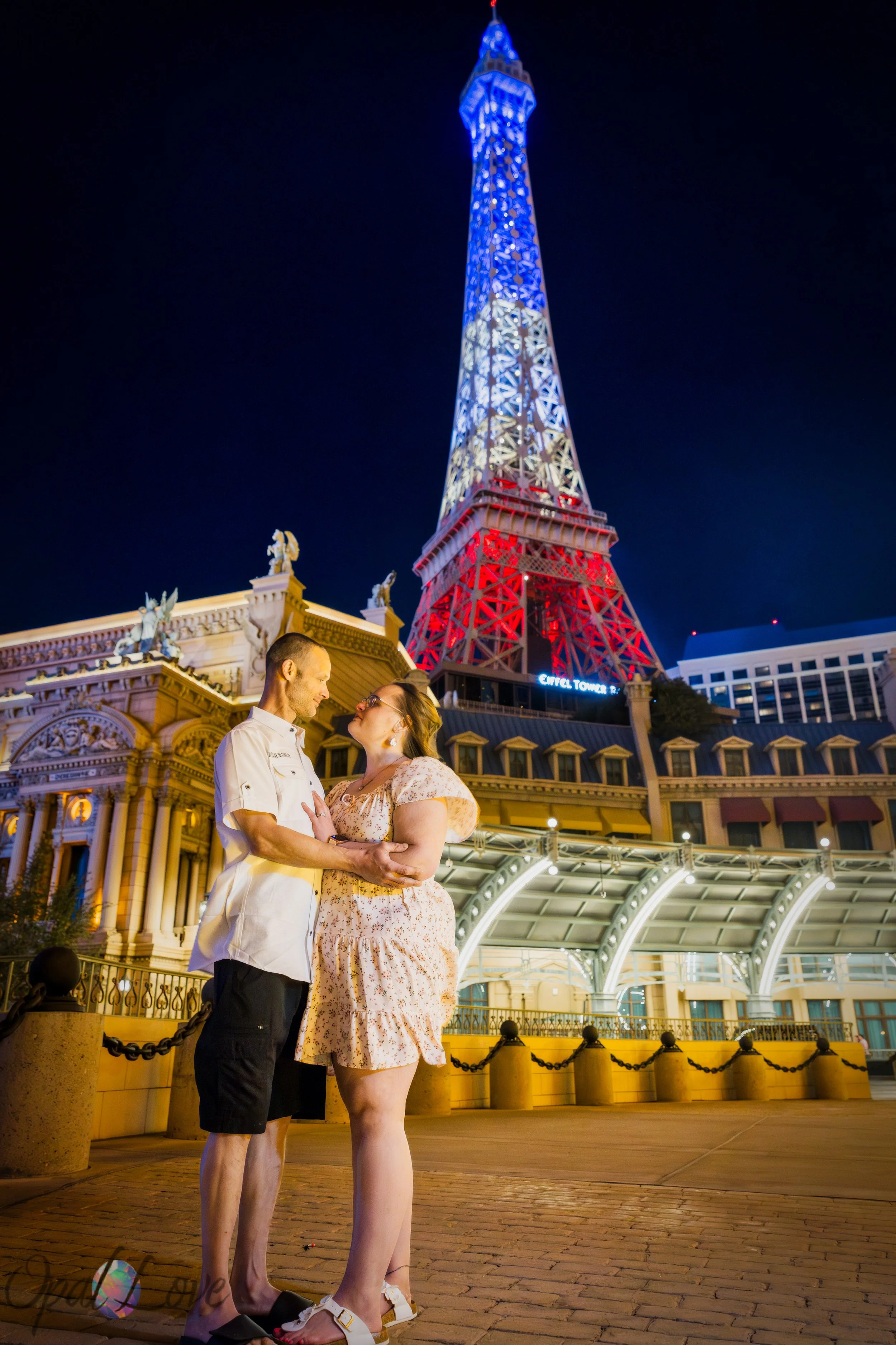 Romantic portrait of couple standing together in front of the illuminated Eiffel Tower at Paris Las Vegas.