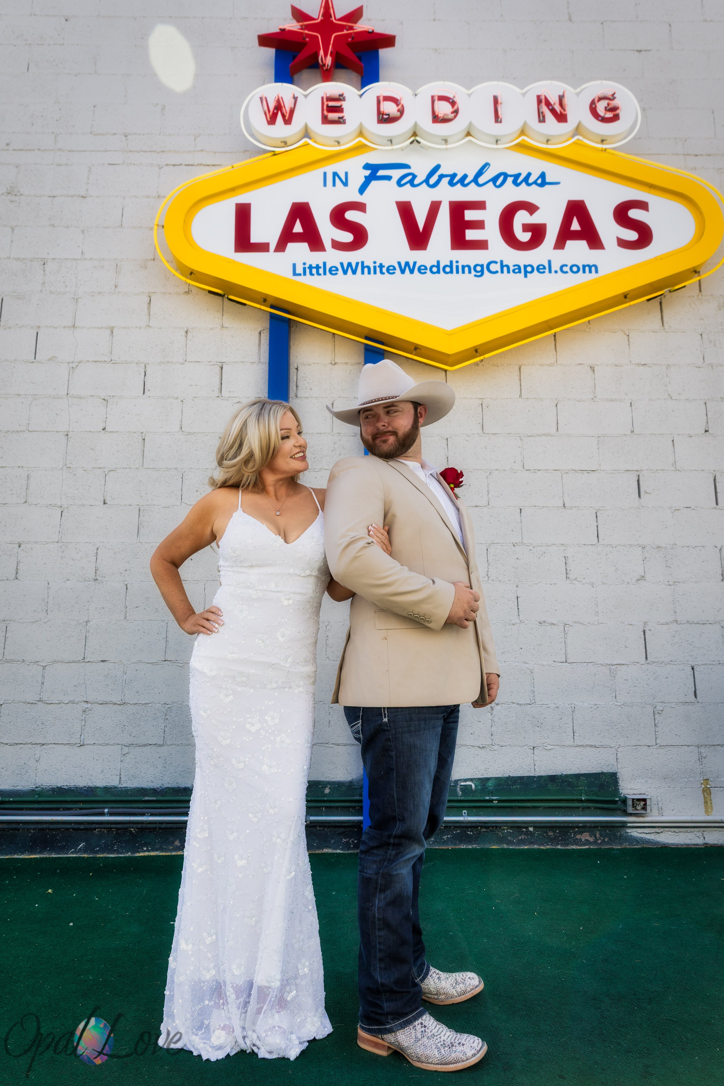 Couple posing beneath the Wedding in Fabulous Las Vegas sign outside Little White Wedding Chapel during a Las Vegas elopement