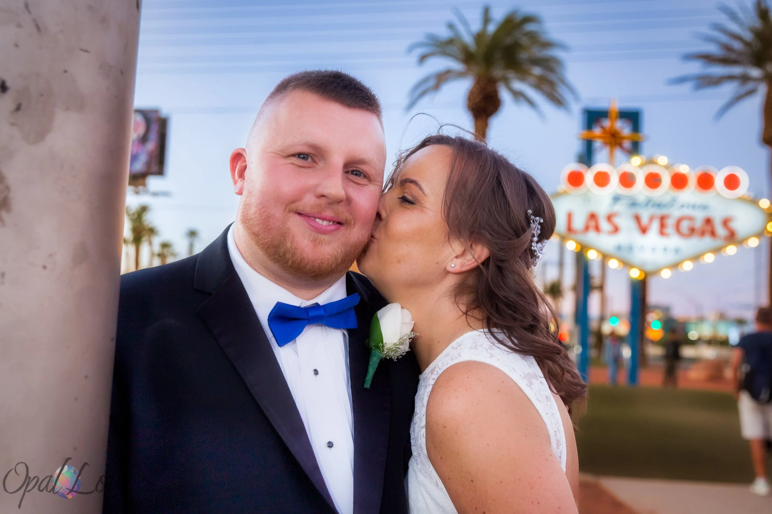 Bride kissing groom’s cheek at the Welcome to Fabulous Las Vegas Sign.
