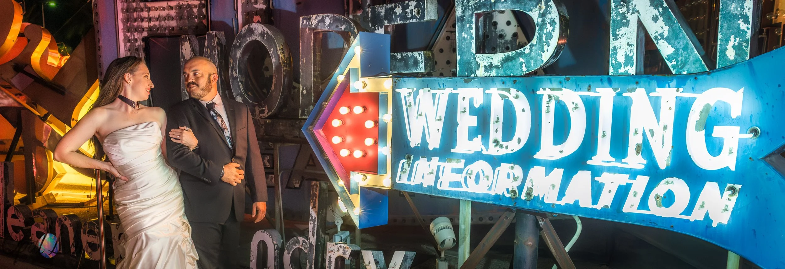 Couple posing beside a vintage Wedding Information neon sign at the Neon Museum in Las Vegas.