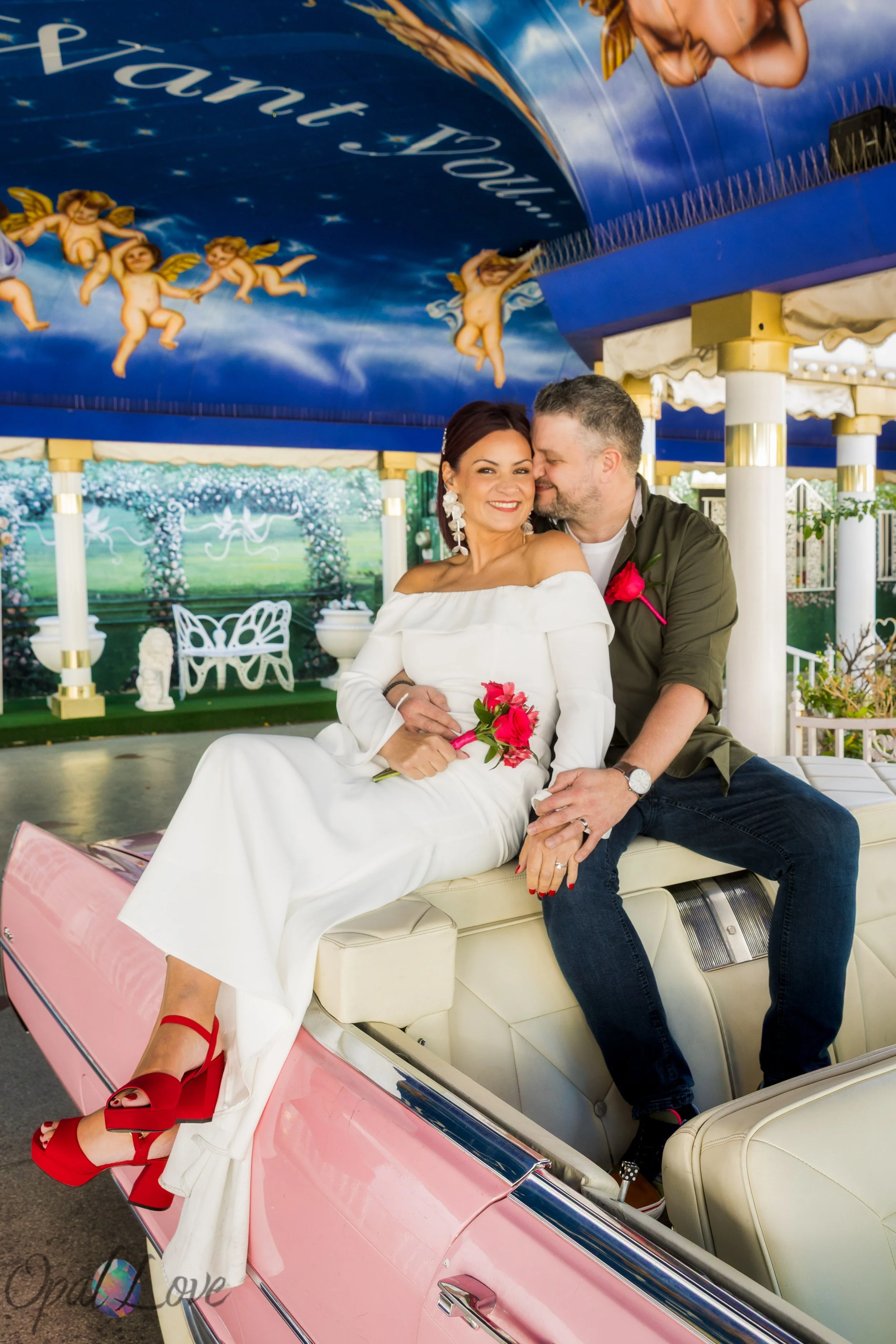 Bride and groom kissing while sitting in the pink Cadillac at A Little White Wedding Chapel.