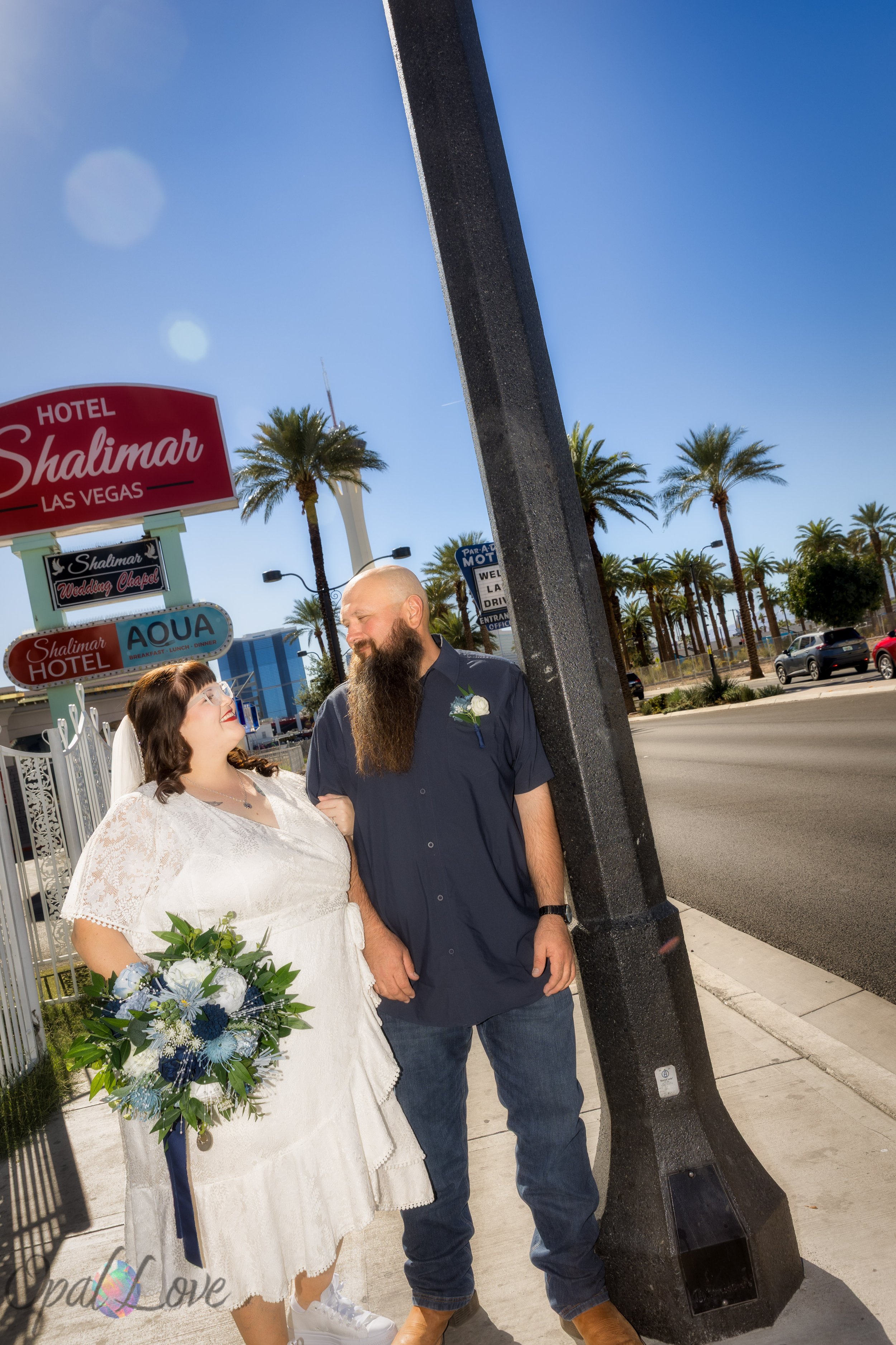 Couple walking and laughing near the Shalimar Hotel sign on Las Vegas Boulevard