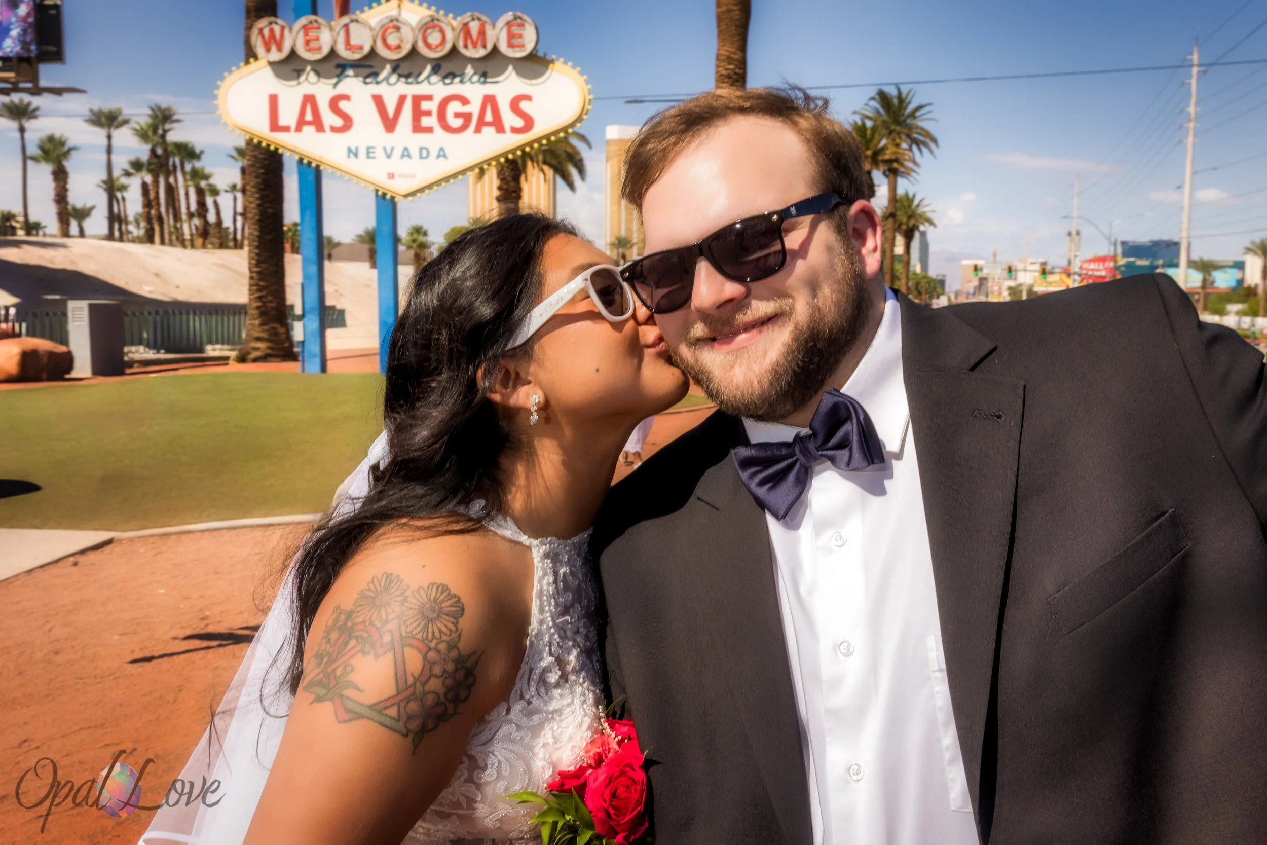 Bride kissing groom on the cheek at the Welcome to Fabulous Las Vegas sign.