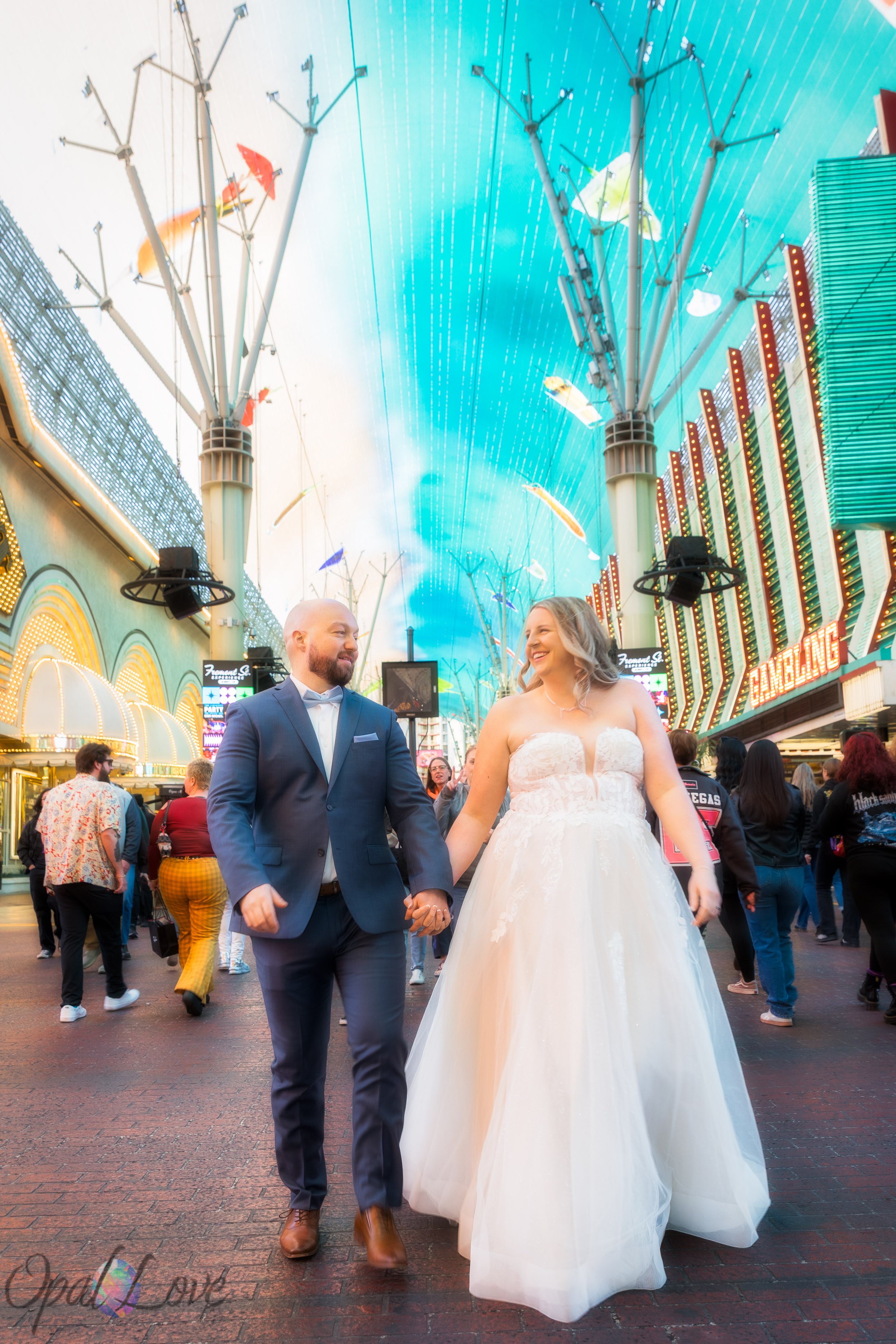 Newlyweds holding hands beneath the Viva Vision canopy on Fremont Street in downtown Las Vegas.