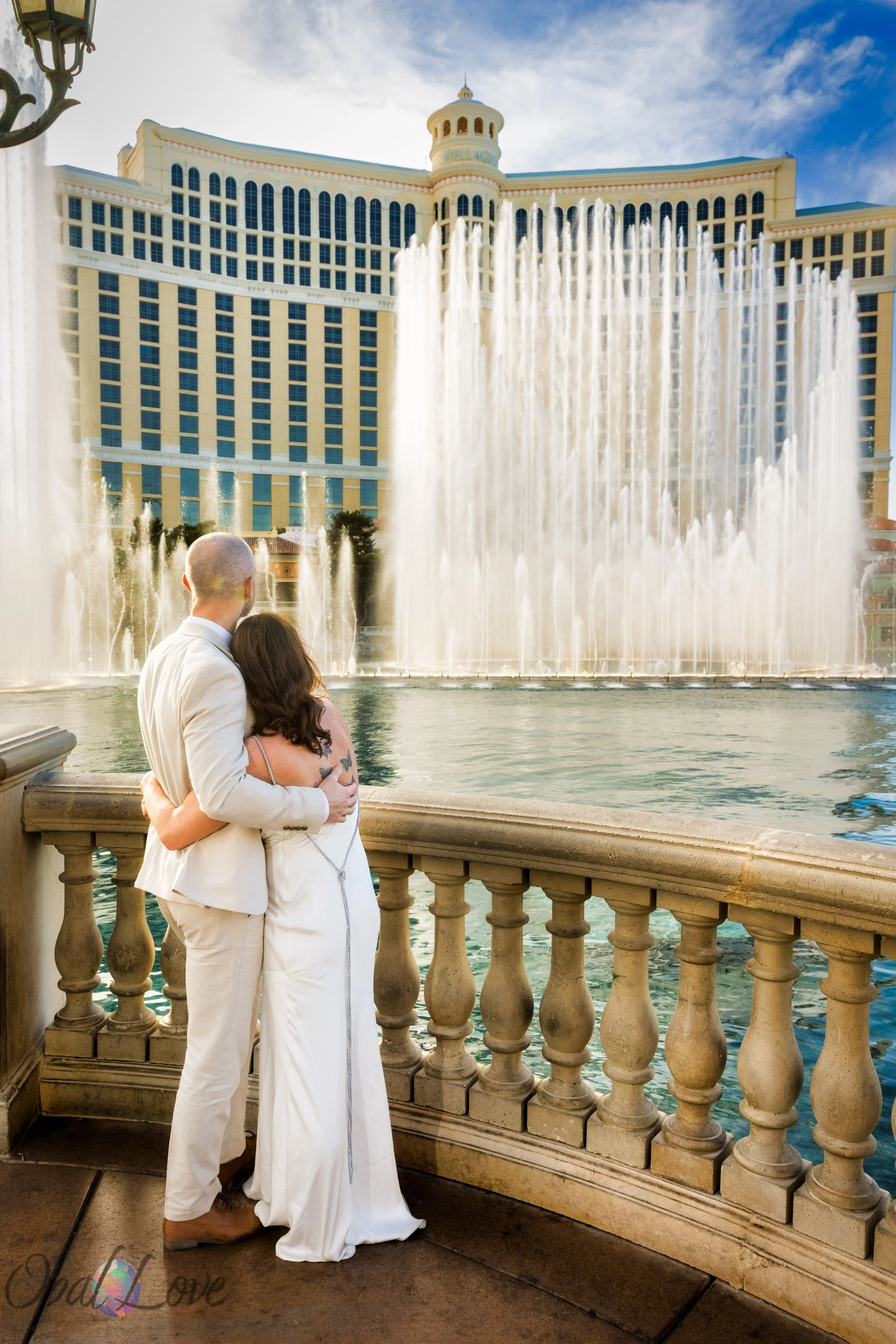 Bride and groom embracing with the Bellagio fountains spraying in the background.