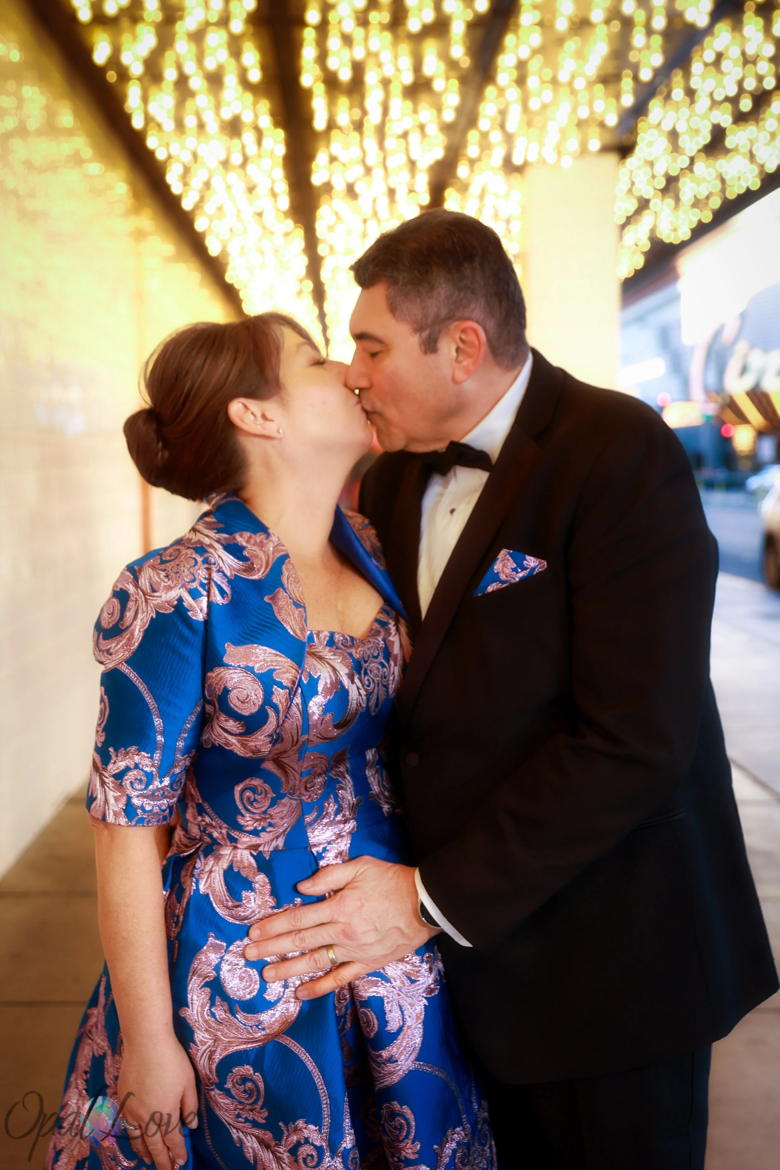 Couple sharing a kiss under the golden lights of a Fremont Street walkway.