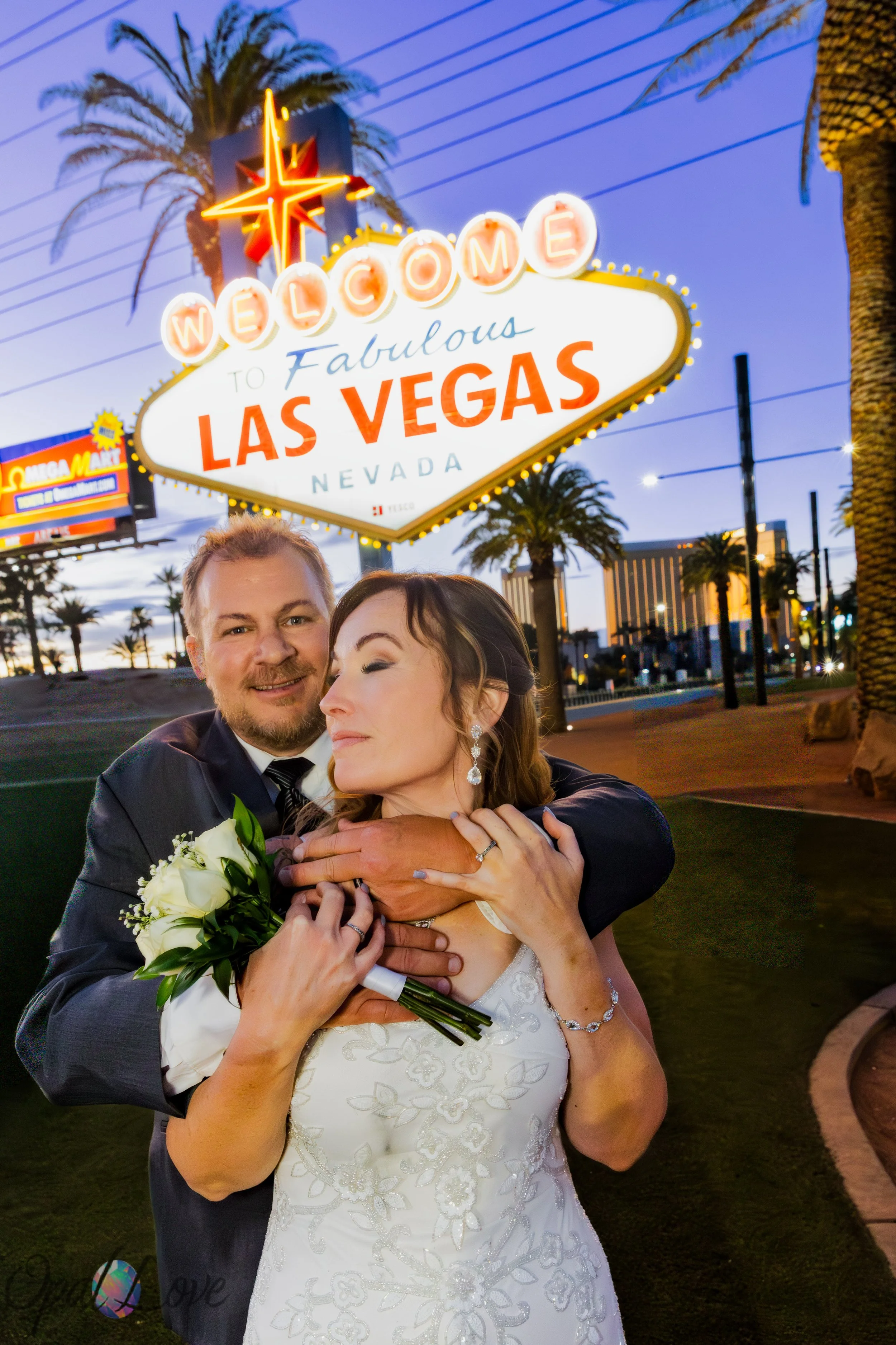Newlyweds posing at the Welcome to Fabulous Las Vegas sign during their Las Vegas wedding photo tour.