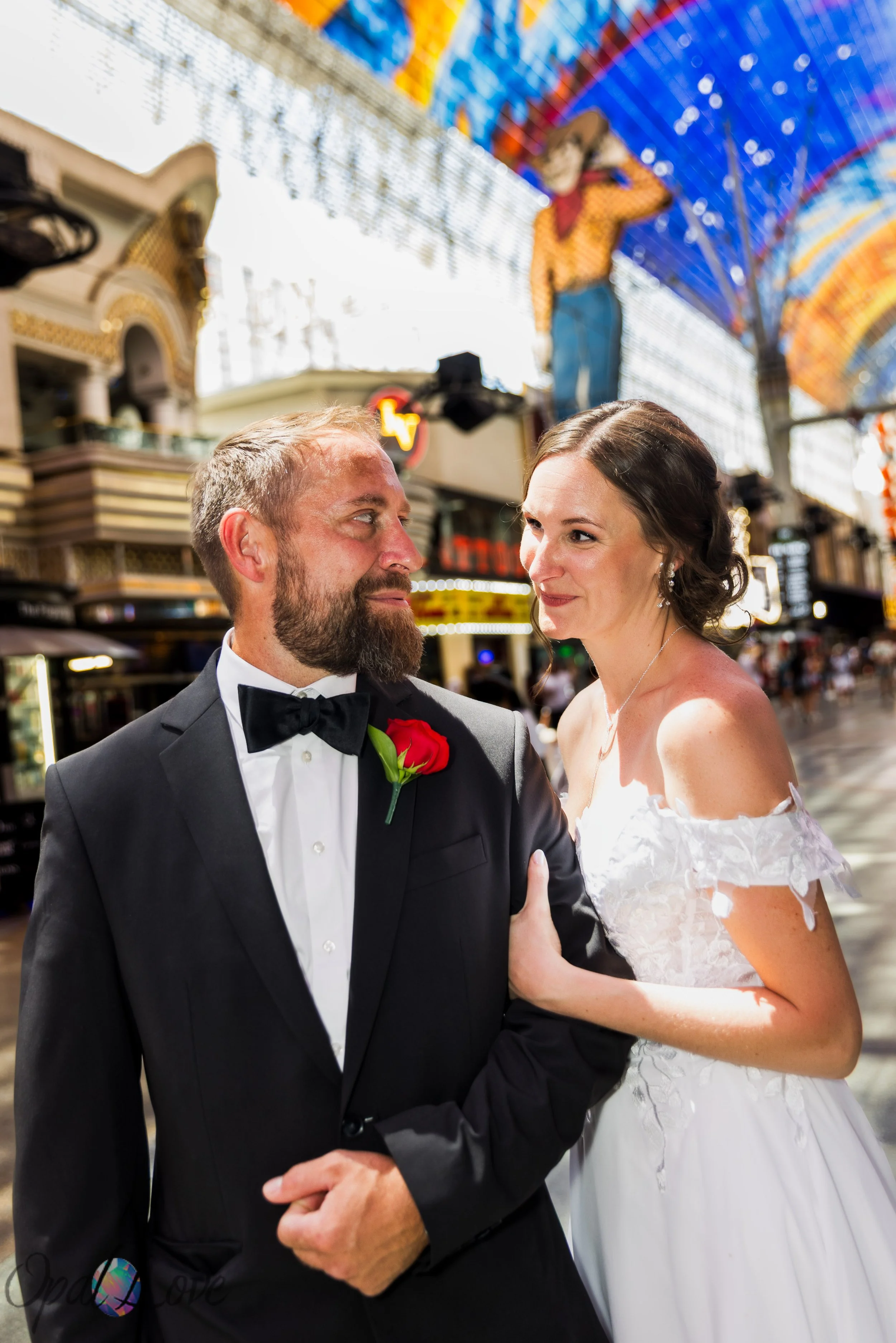 Kari and Rickie posing beneath the Fremont Street Experience canopy during their Las Vegas wedding photography session.