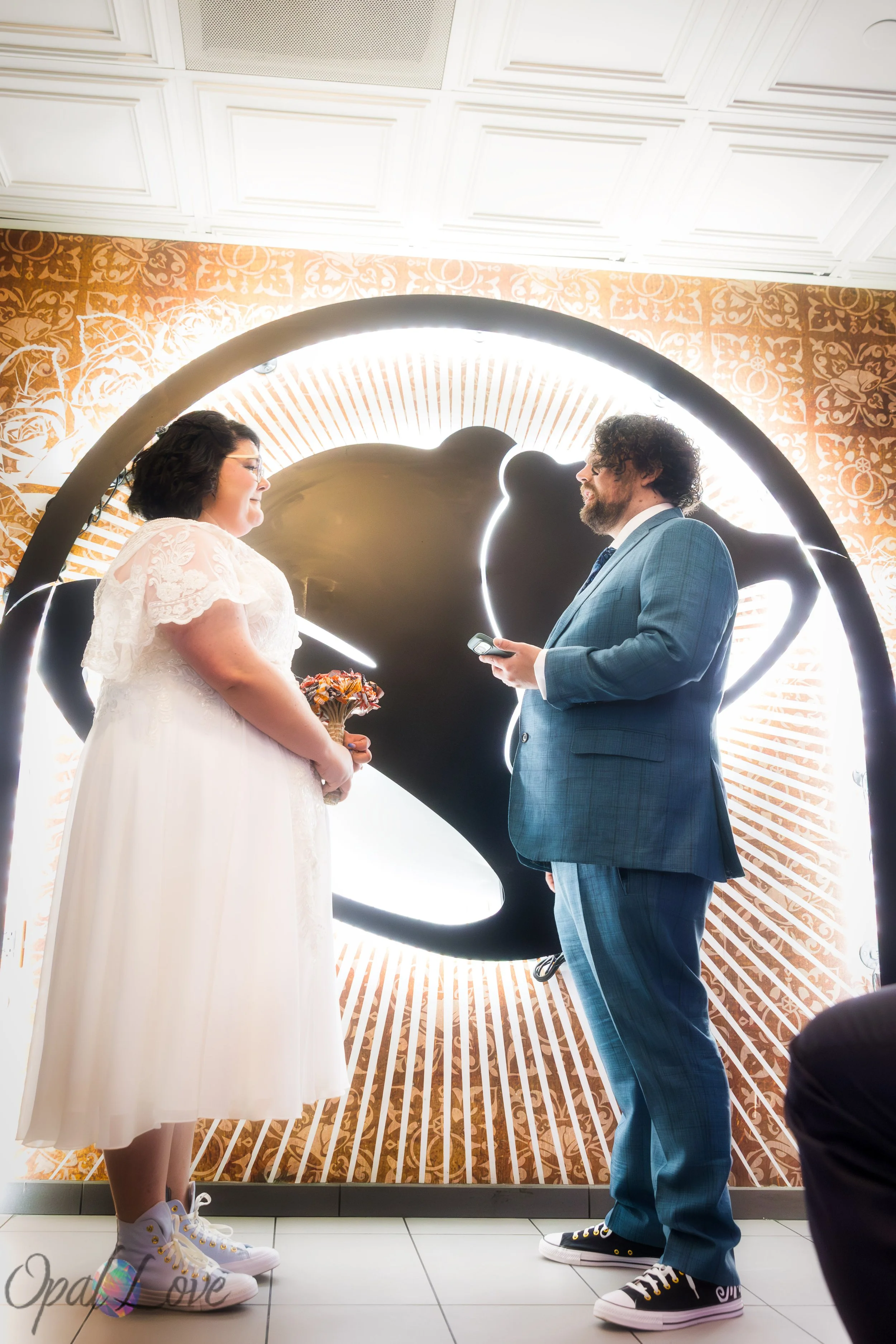 Couple exchanging vows under the illuminated Taco Bell bell sign.
