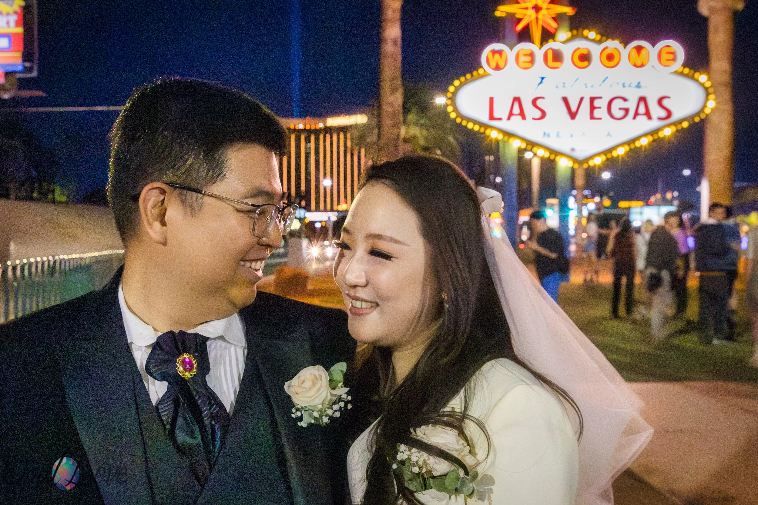 Couple smiling together at Welcome to Las Vegas sign at night