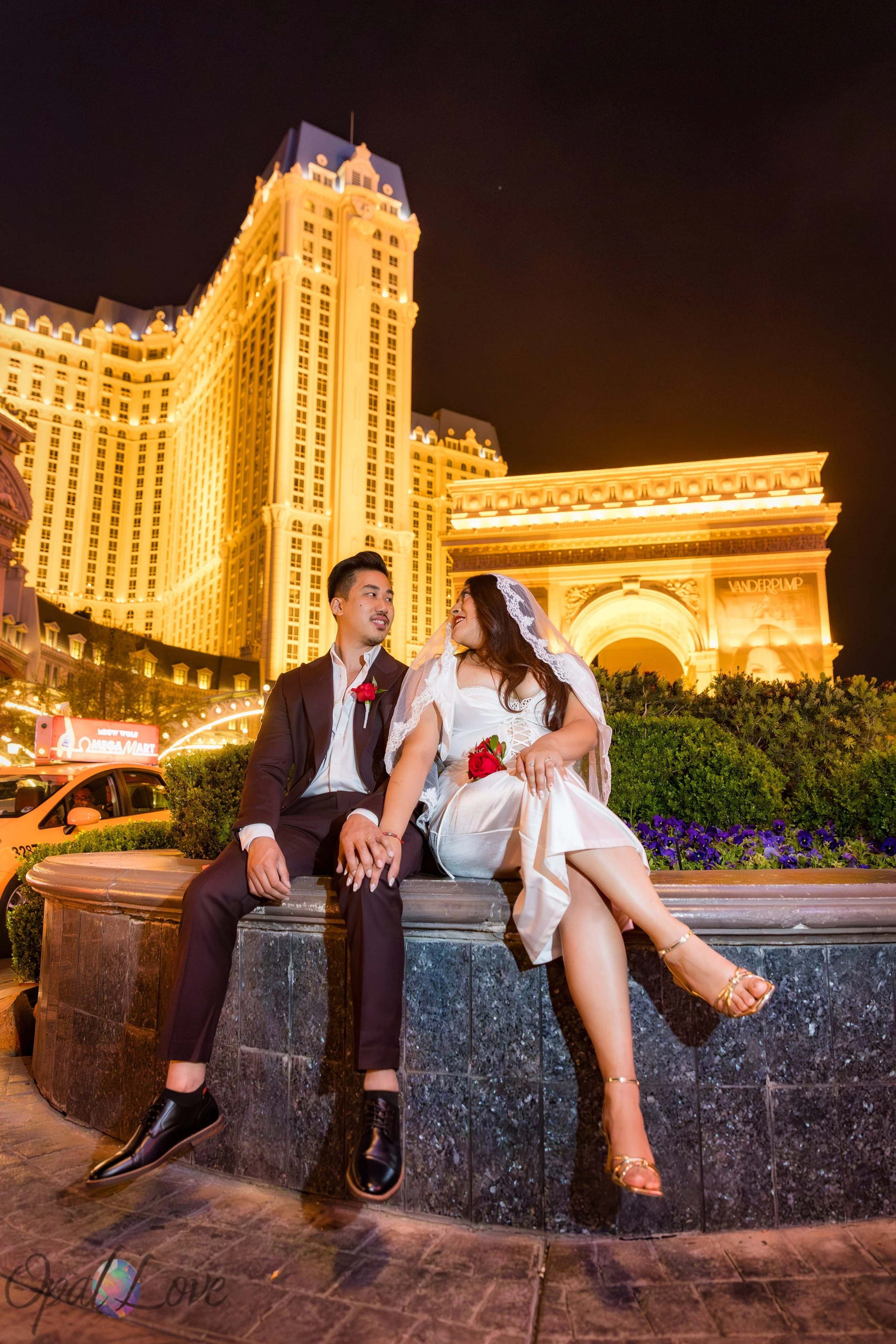 Newlyweds sitting together in front of the Paris Las Vegas hotel buildings during their Las Vegas Strip photo tour.