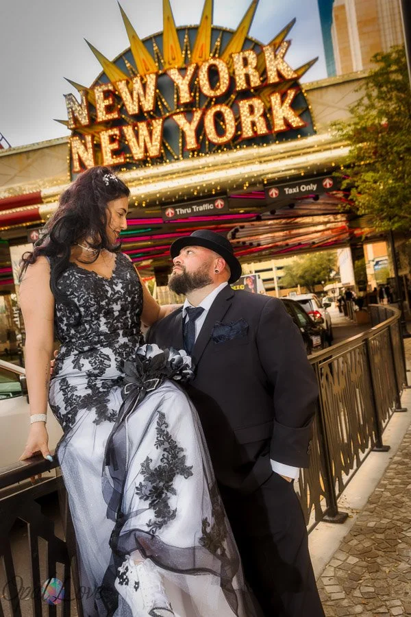 Newlywed couple posing beneath the New York-New York sign on the Las Vegas Strip.