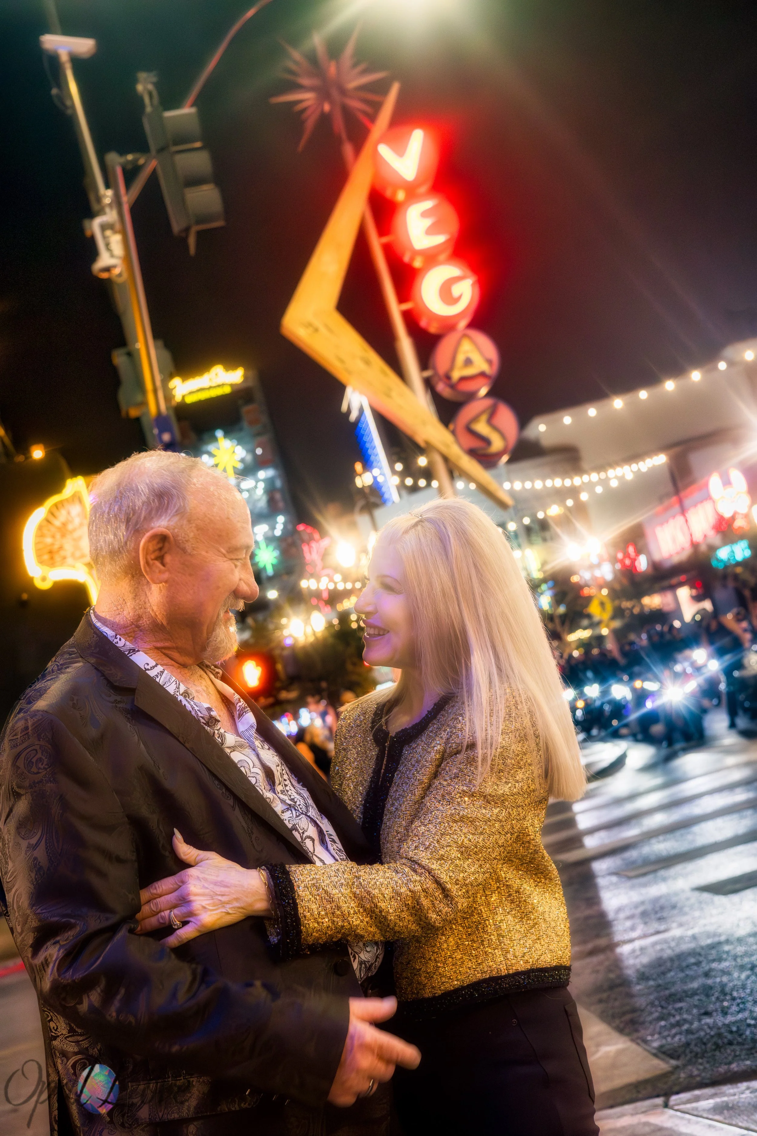 Couple smiling under the neon Vegas sign in Fremont East during their anniversary photo session.