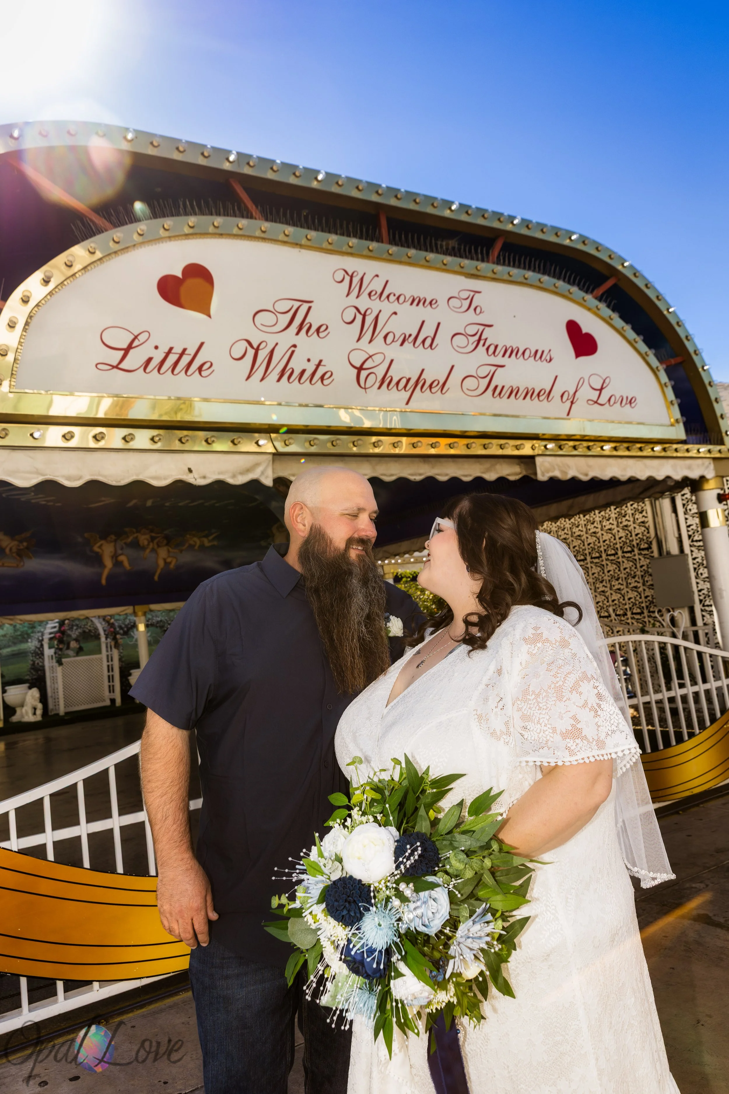 Couple smiling under the Tunnel of Love sign at A Little White Chapel.