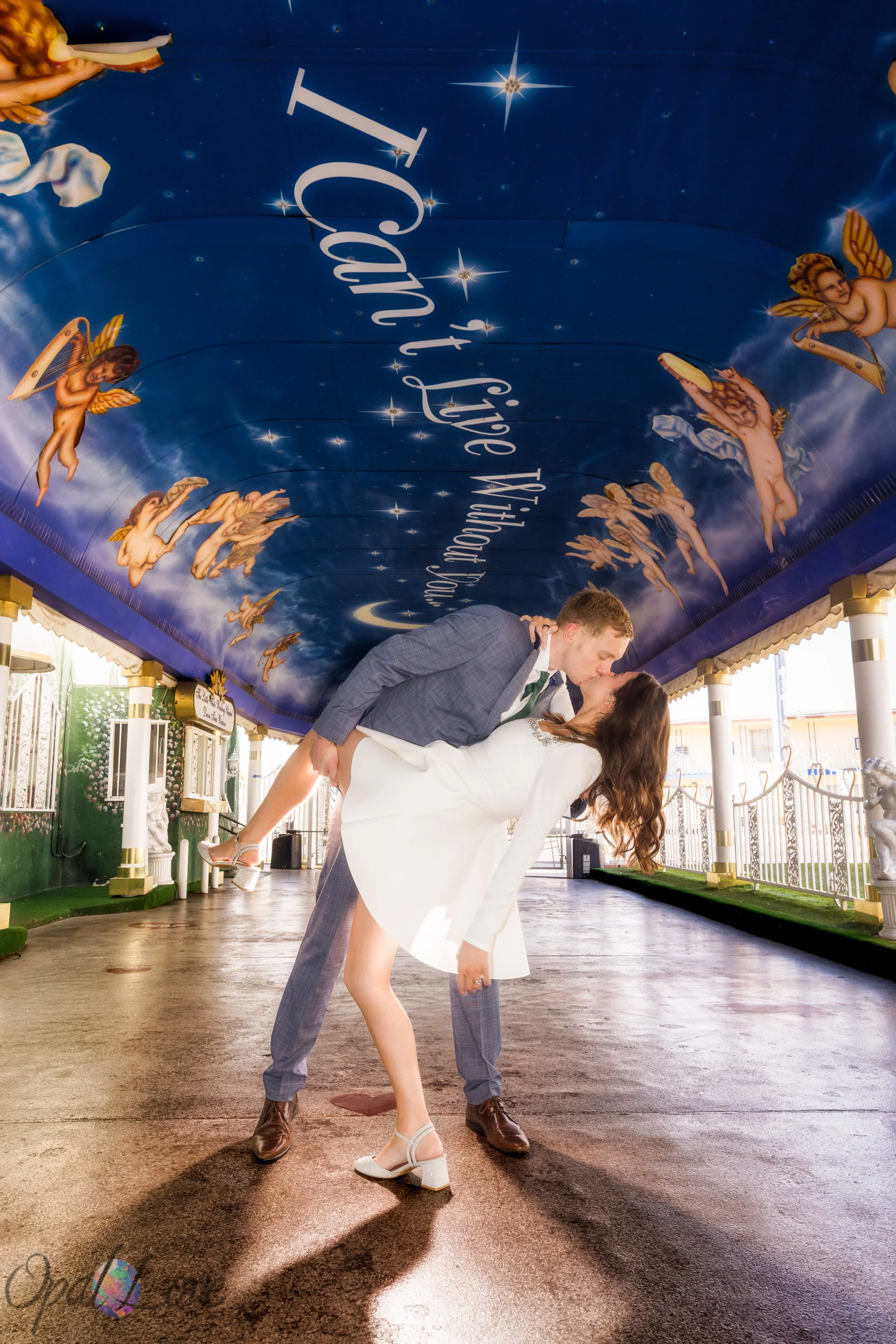 Groom dipping bride beneath the “I Can’t Live Without You” ceiling mural at A Little White Wedding Chapel in Las Vegas.