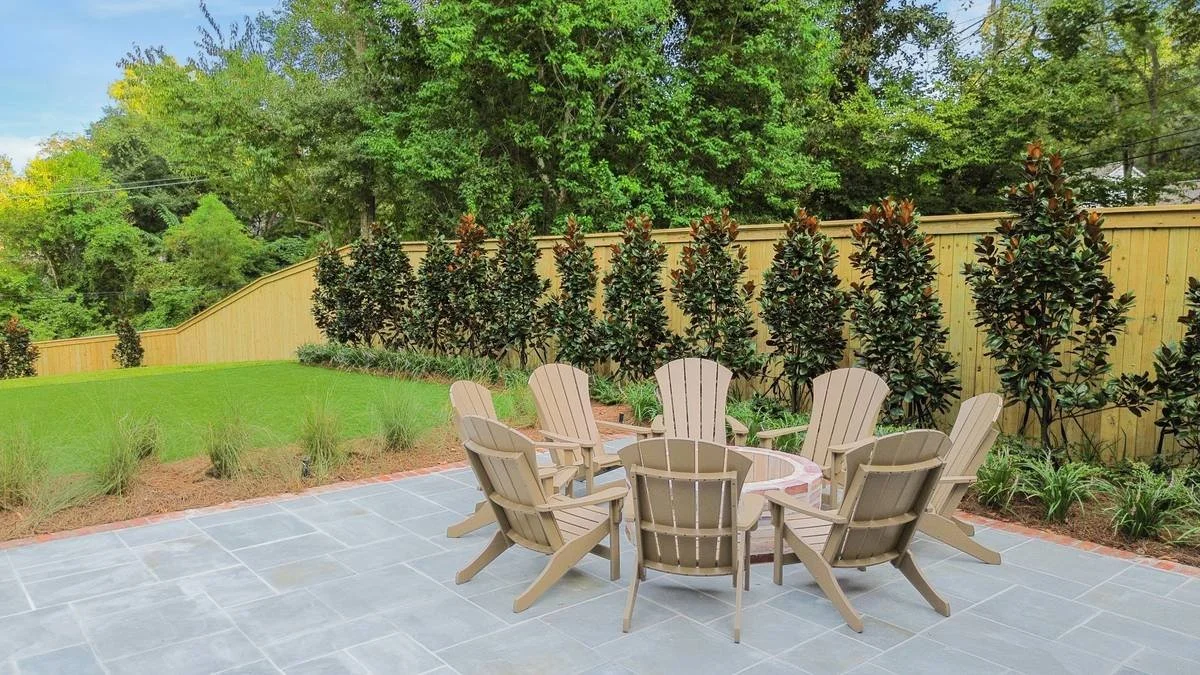 Fire pit seating on bluestone with magnolia screening along the fence — Flora Landscape Contractors