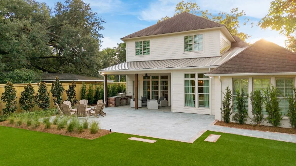 Sunlit backyard terrace with columnar evergreens along the house — Flora Landscape Contractors
