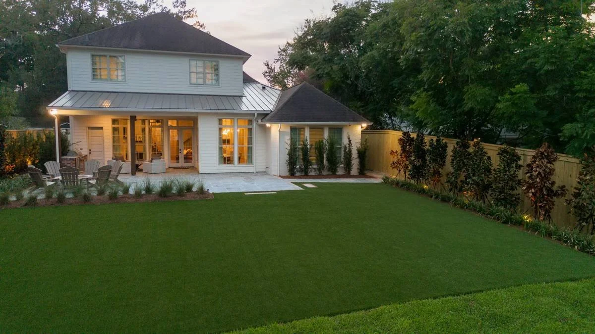 Backyard lawn and terrace at twilight with landscape lighting on — Flora Landscape Contractors