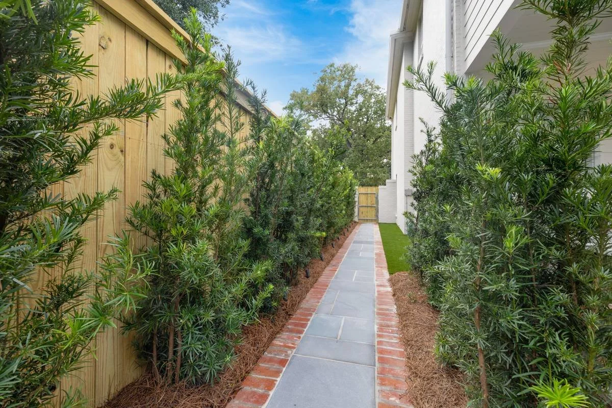 Bluestone side walkway with brick borders between evergreen plantings — Flora Landscape Contractors