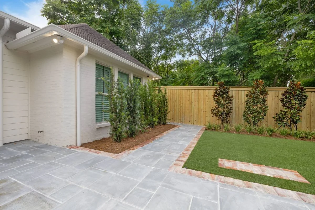 Side yard walkway with brick edging next to a strip of synthetic turf — Flora Landscape Contractors