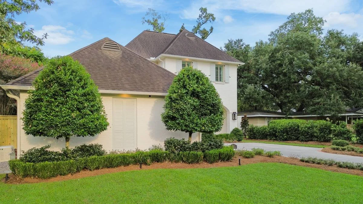 Standard trees and clipped hedges along the garage side of the front lawn — Flora Landscape Contractors