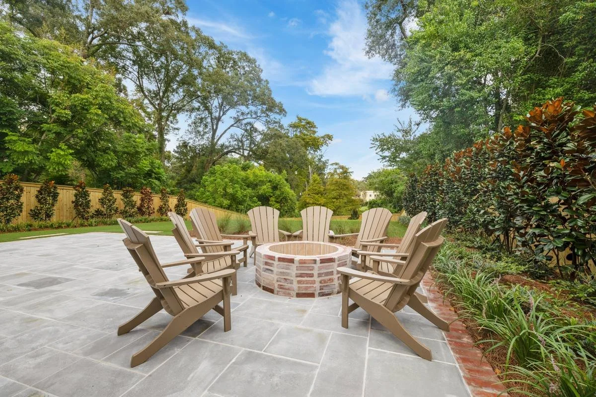 Brick fire pit ringed with Adirondack chairs on a bluestone patio — Flora Landscape Contractors