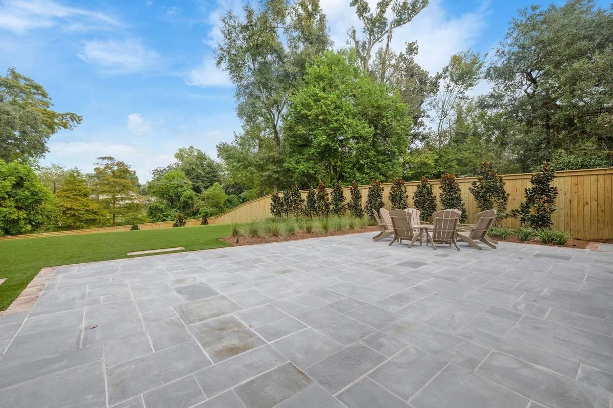 Bluestone terrace facing a wood fence lined with magnolias — Flora Landscape Contractors