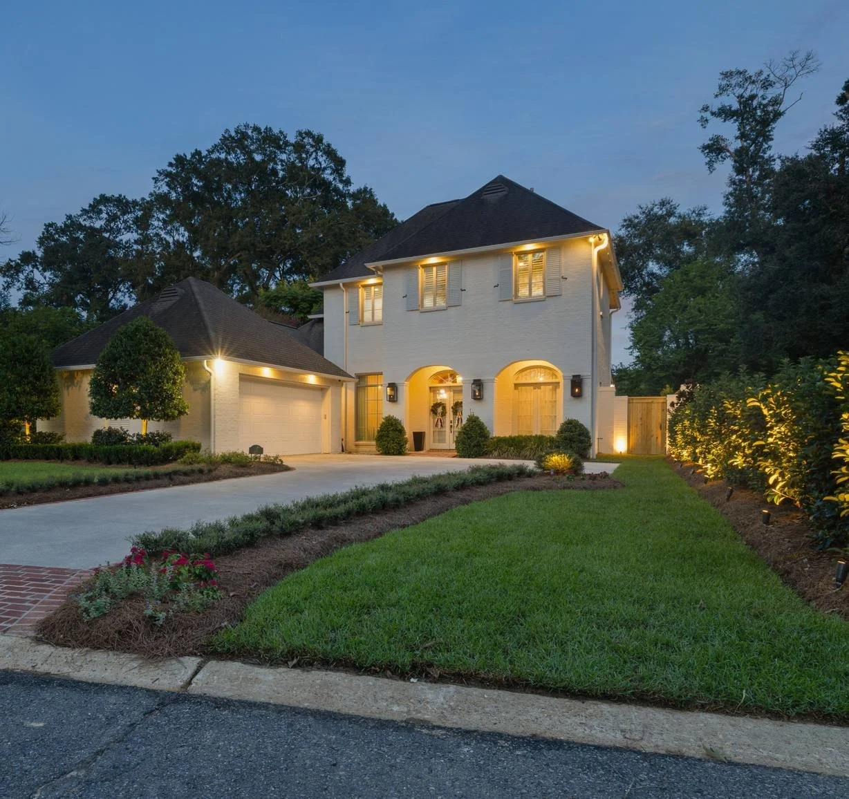 Uplit hedge and front landscape lighting along the driveway at dusk — Flora Landscape Contractors