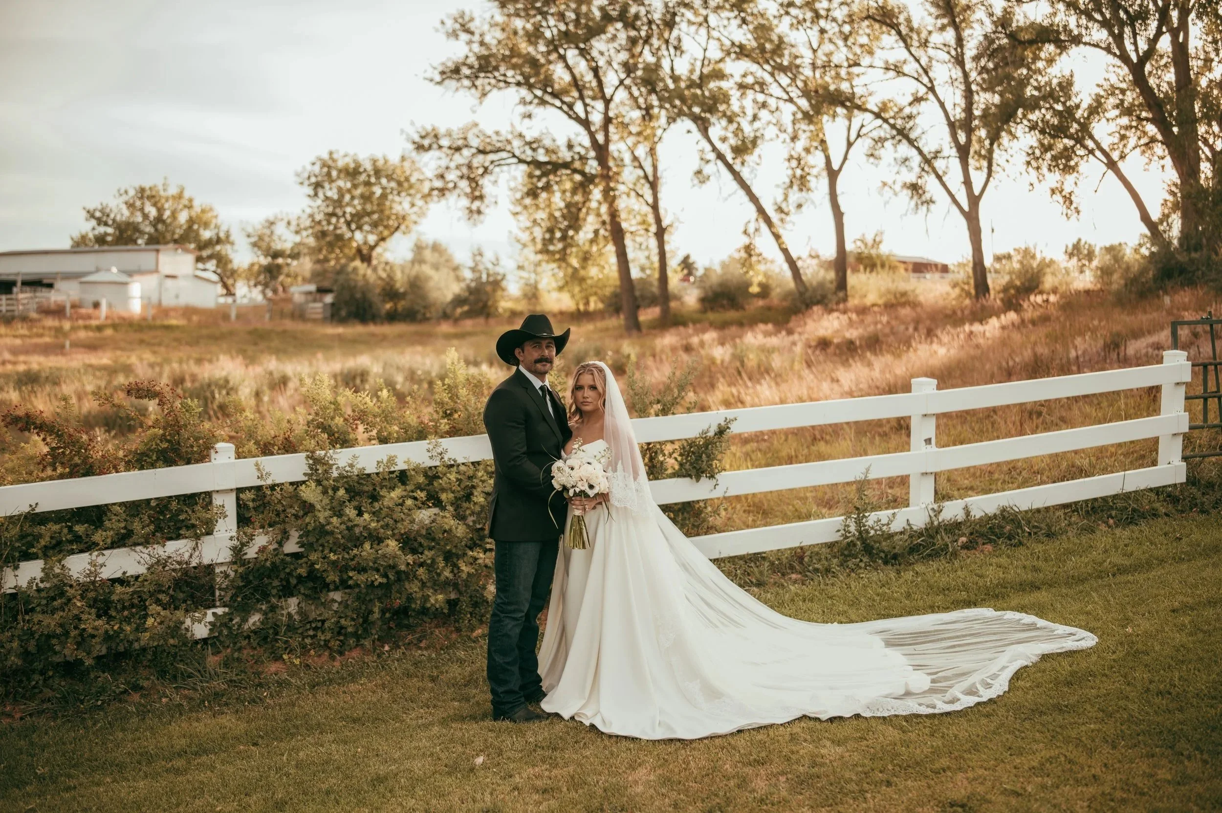 Western luxury bride and groom embracing during an elegant ranch wedding at Camelot Ranch in Billings, Montana with scenic countryside views.