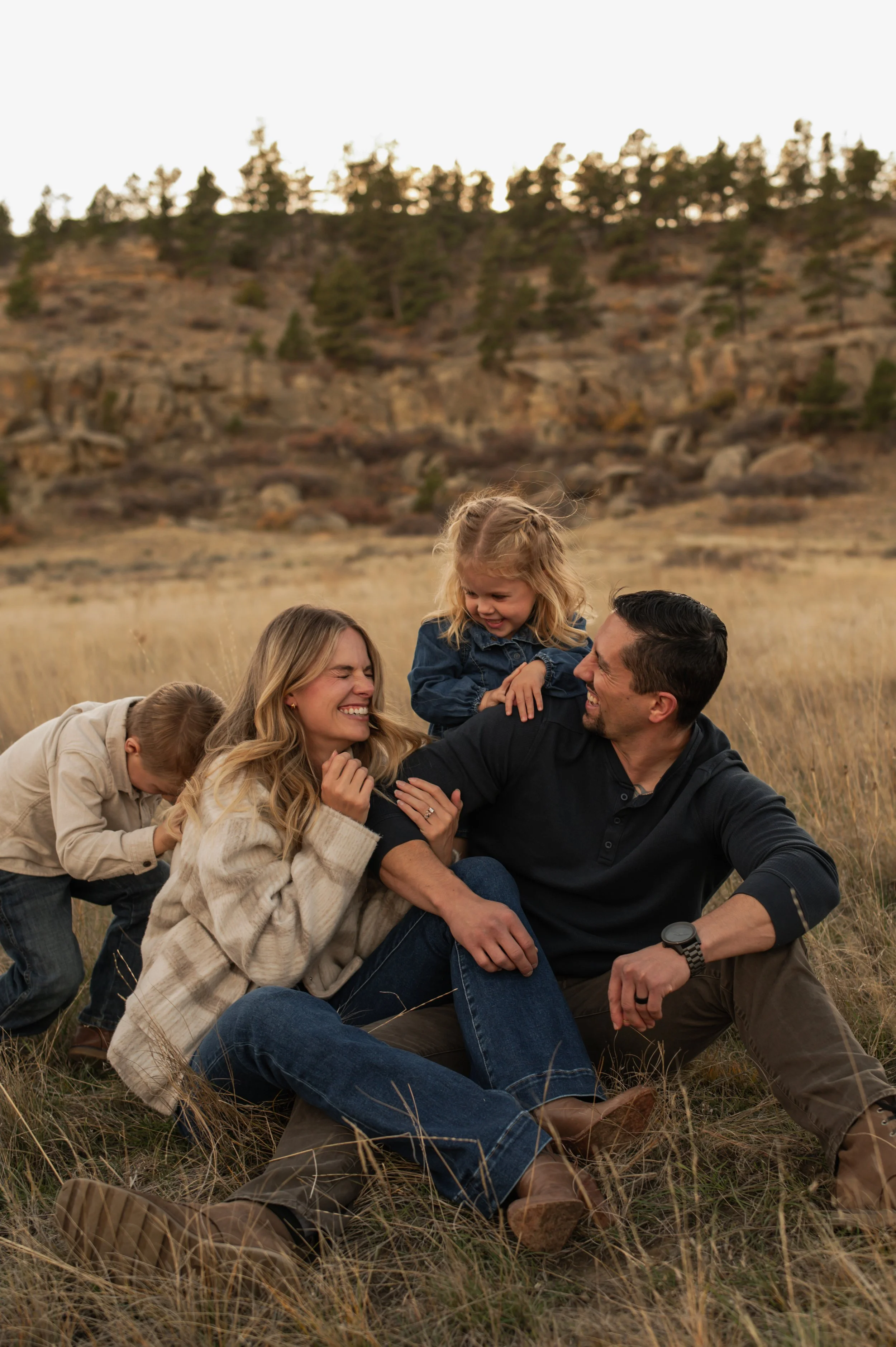 Family portrait session in Billings, Montana with parents and children embracing outdoors during golden hour.