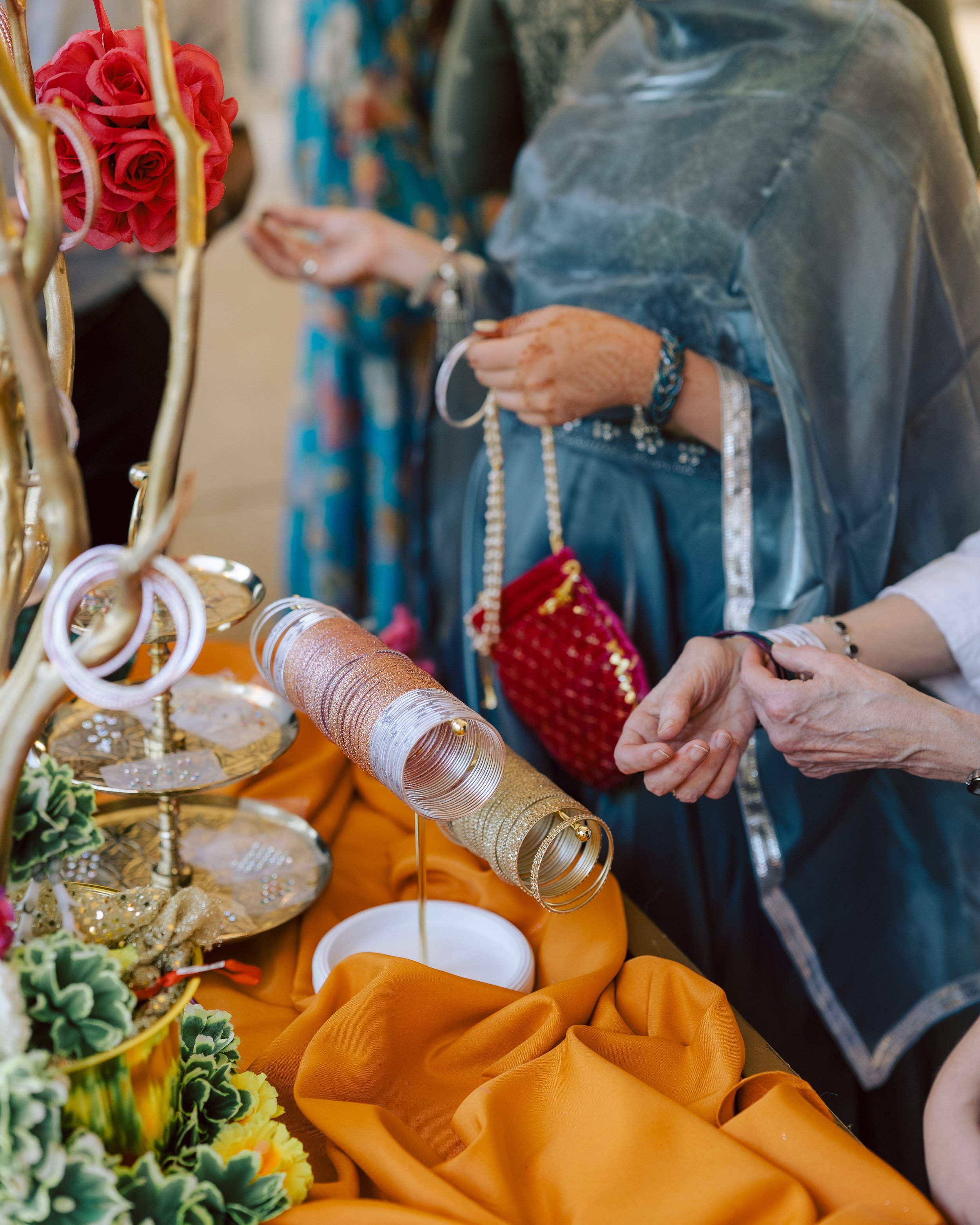 People shopping for jewelry, with colorful bangles on display and orange fabric on the table.