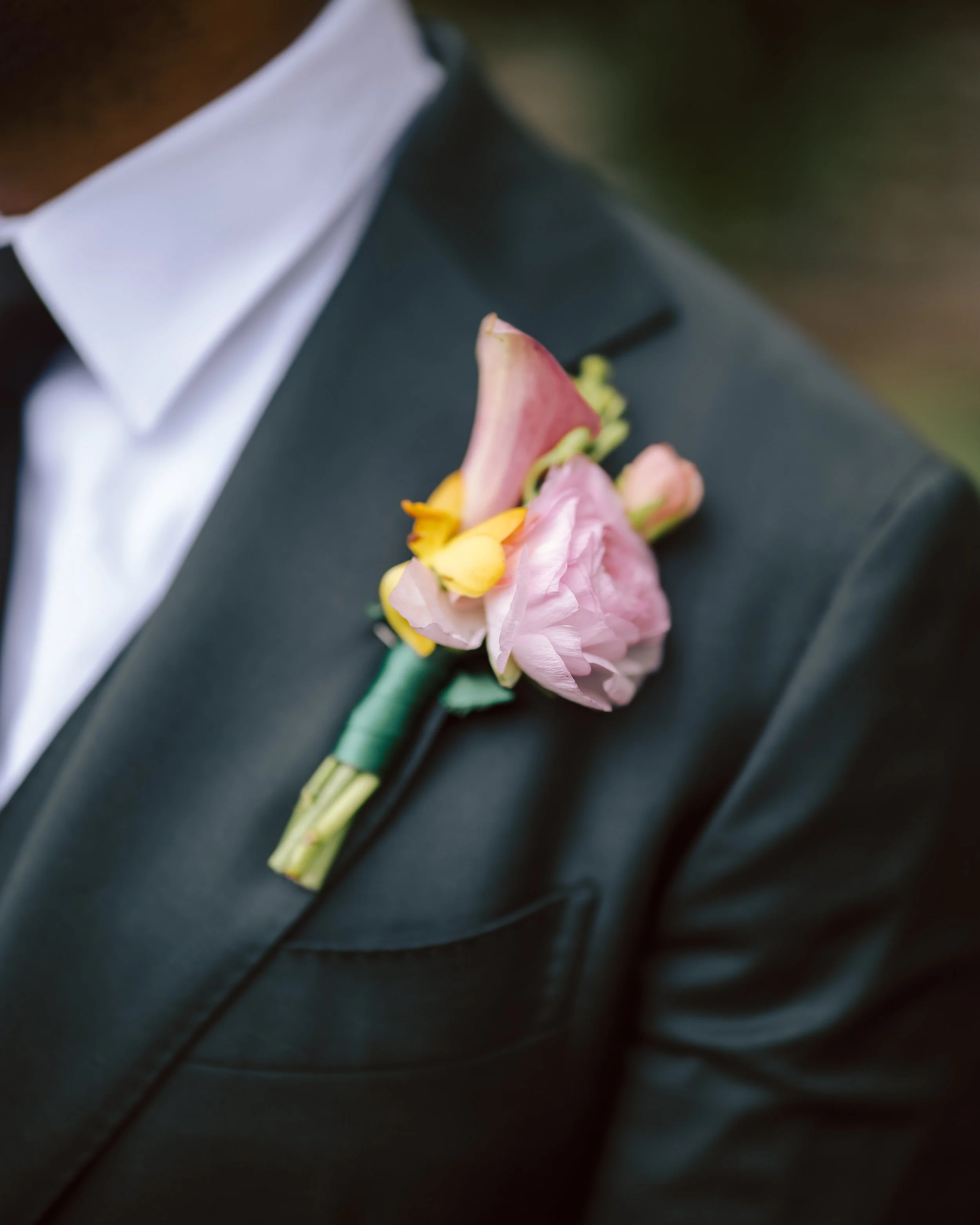 Close-up of a suit with a pink and yellow boutonniere on the lapel.