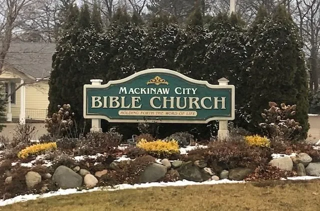 Sign for Mackinaw City Bible Church with landscaping and bushes in the foreground