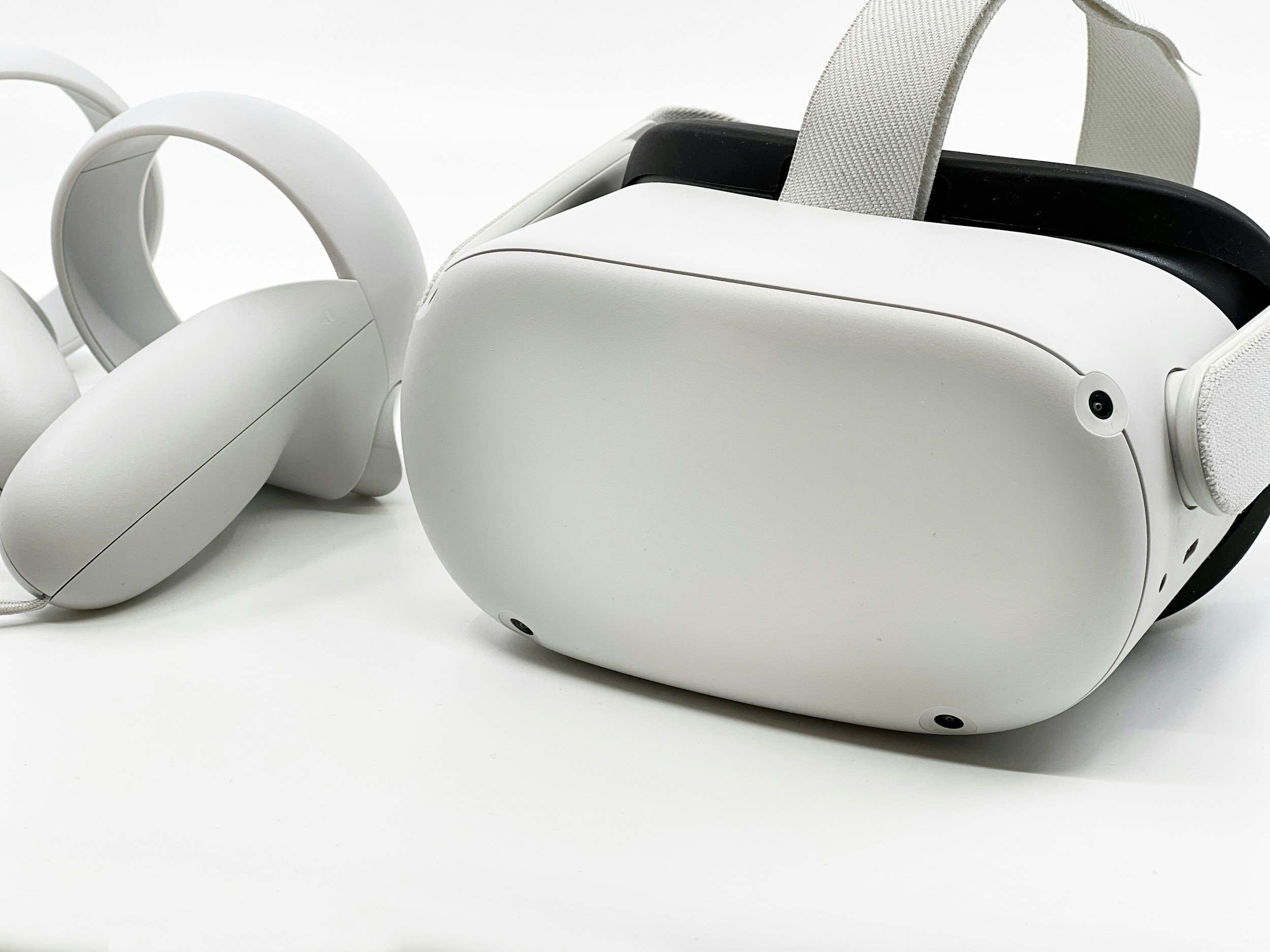White virtual reality headset and white VR headphones on a white background.