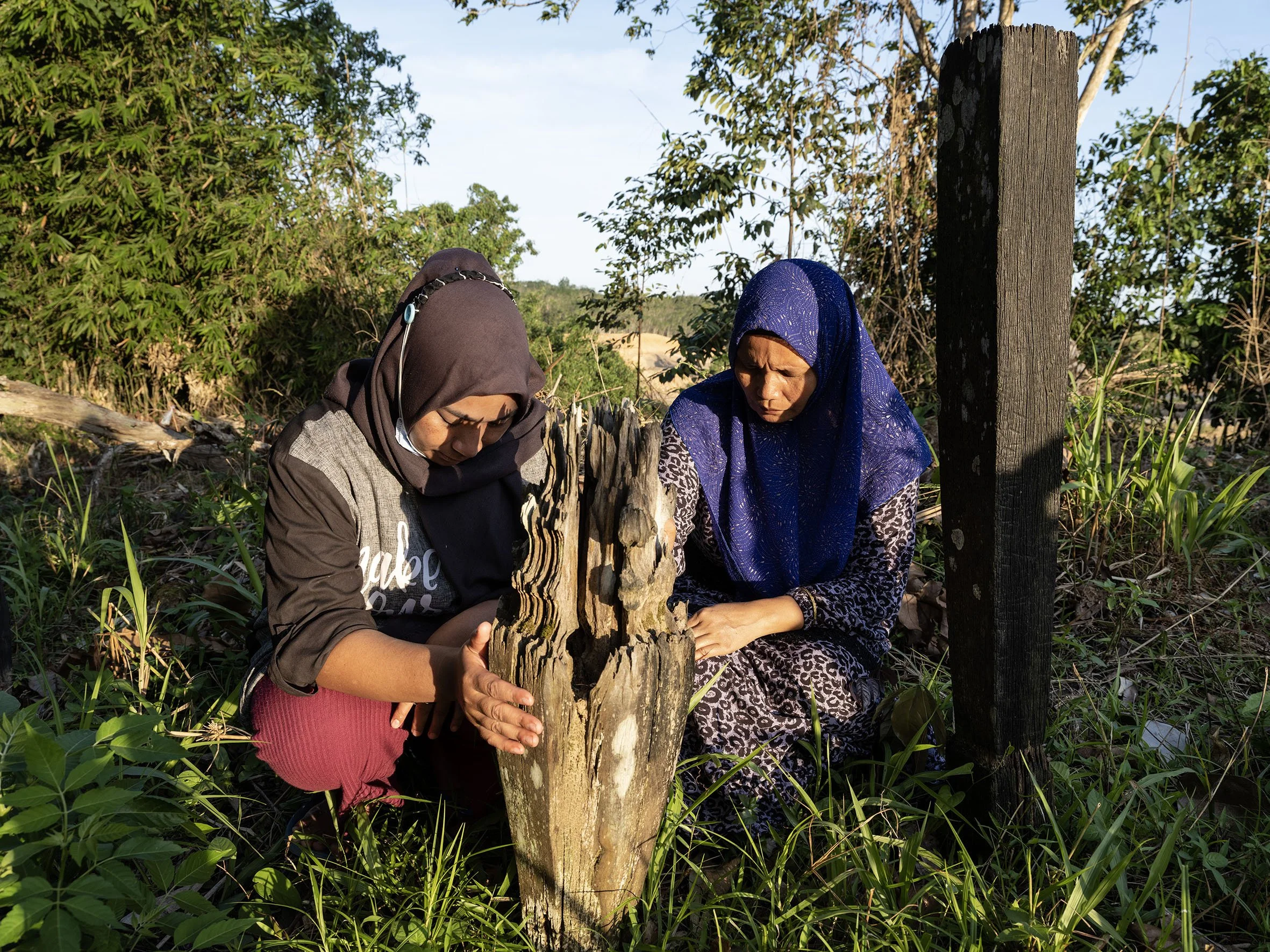Samira and Sabardin pray at the graves of their ancestors in the ancient cemetery of the indigenous Balik tribe in the village of Sepaku. The cemetery was located on the construction site of the new Intake Dam and was later removed. August 30, 2022