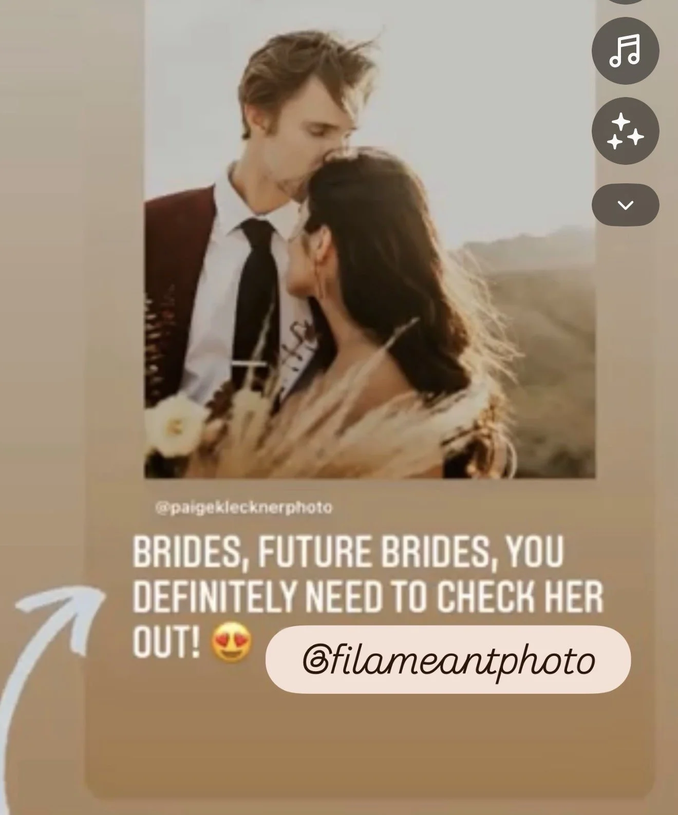 A photograph of a newlywed couple outdoors during sunset, with the groom kissing the bride on the forehead. The bride holds a bouquet of dried flowers and wears a white dress, while the groom is dressed in a suit with a tie. The scenery includes mountains and a clear sky in the background.