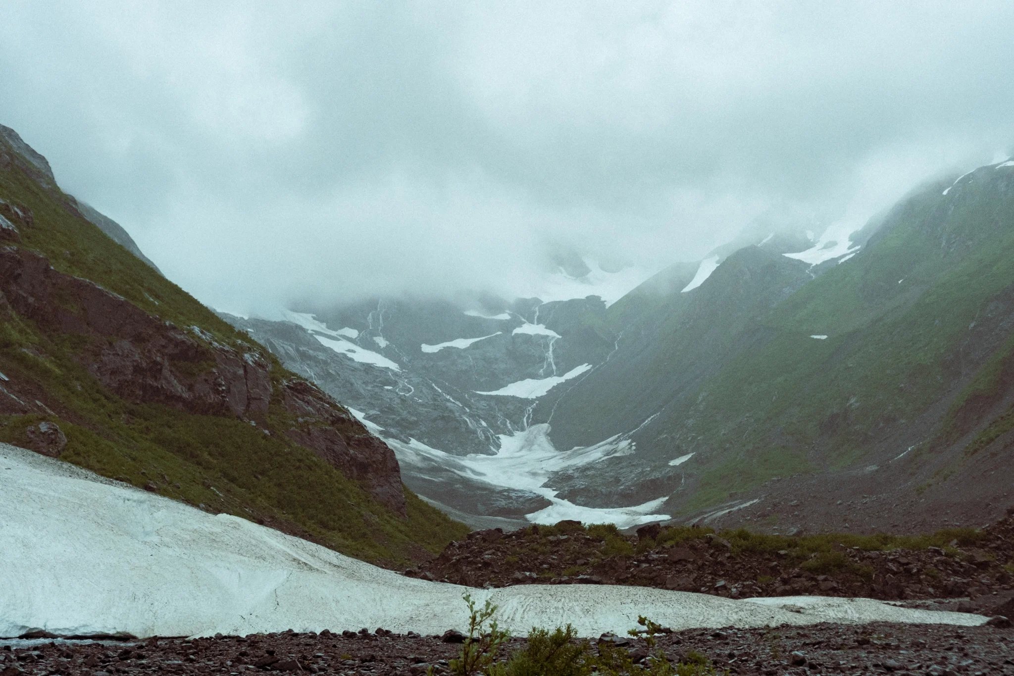 blue and white glacier ice in green valley of Byron glacier, Alaska