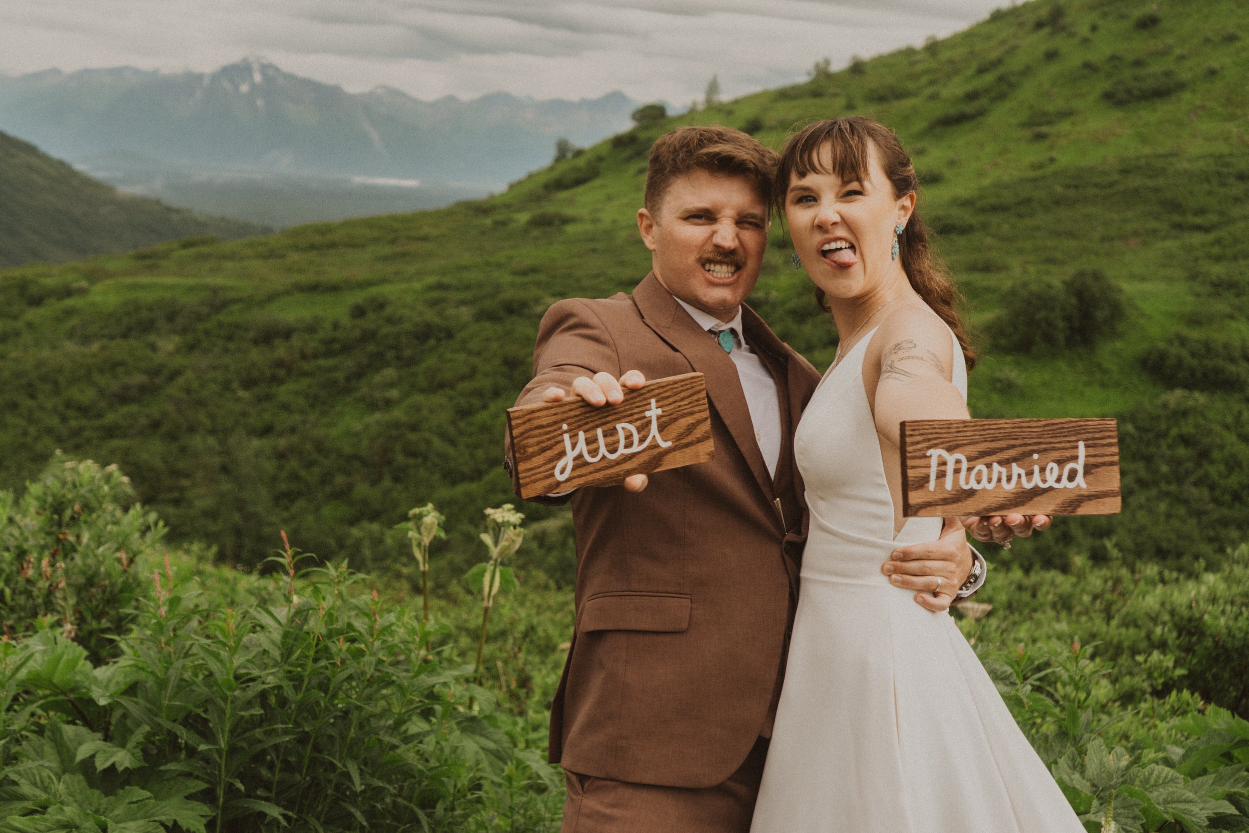 couple holding just married signs on their elopement to Hatcher Pass