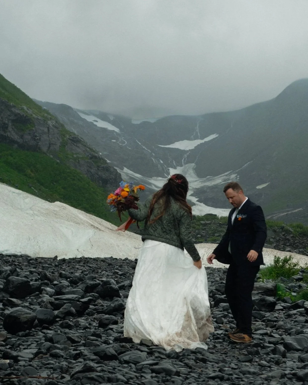 groom marveling atbride holding her flowers standing at Byron glacier in Alaska