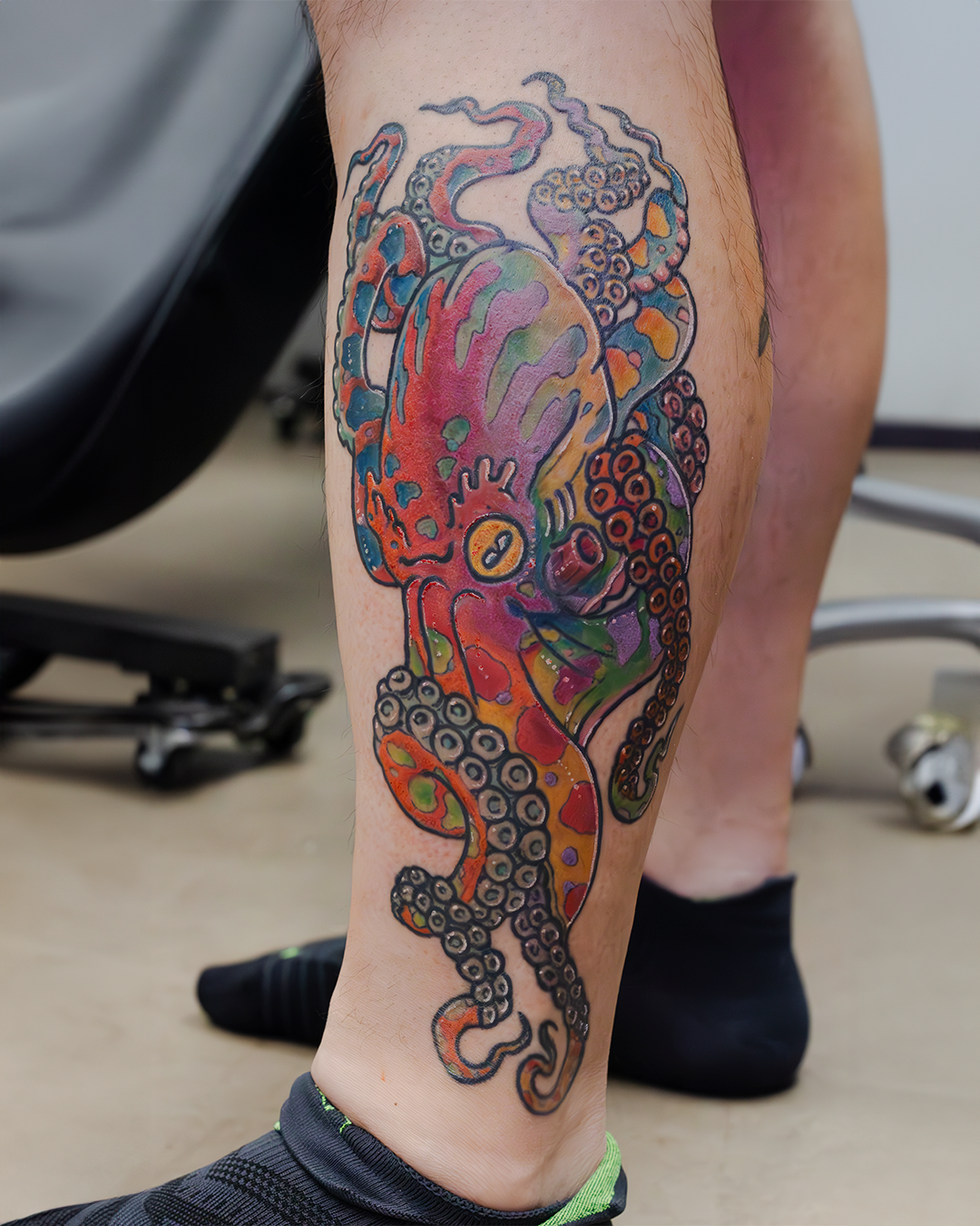 Colorful tattoo of an octopus with abstract and vibrant elements on a person's calf.